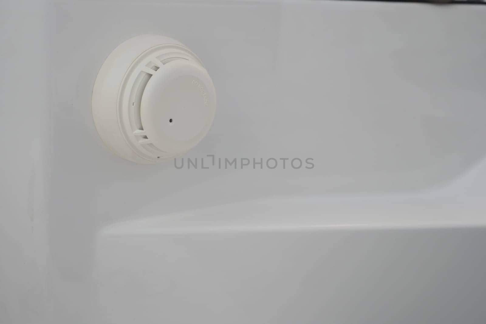 A smoke detector is mounted on the bathroom wall for fire safety.