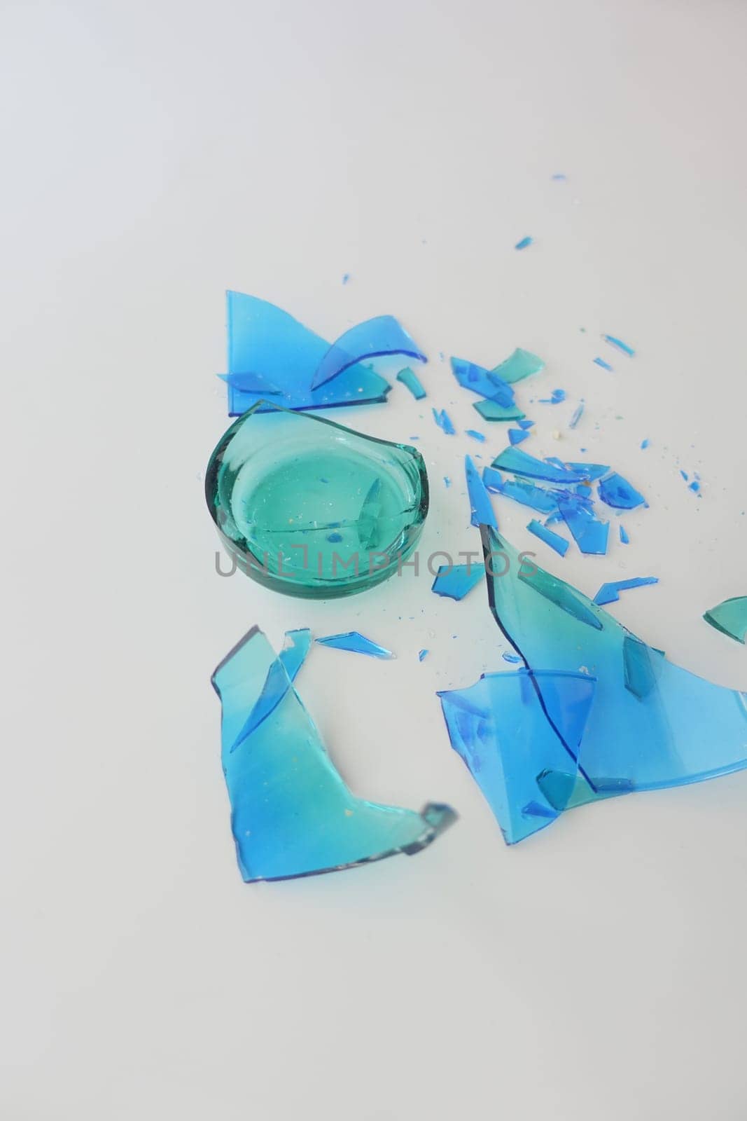 Bright turquoise glass pieces are scattered across a white surface.