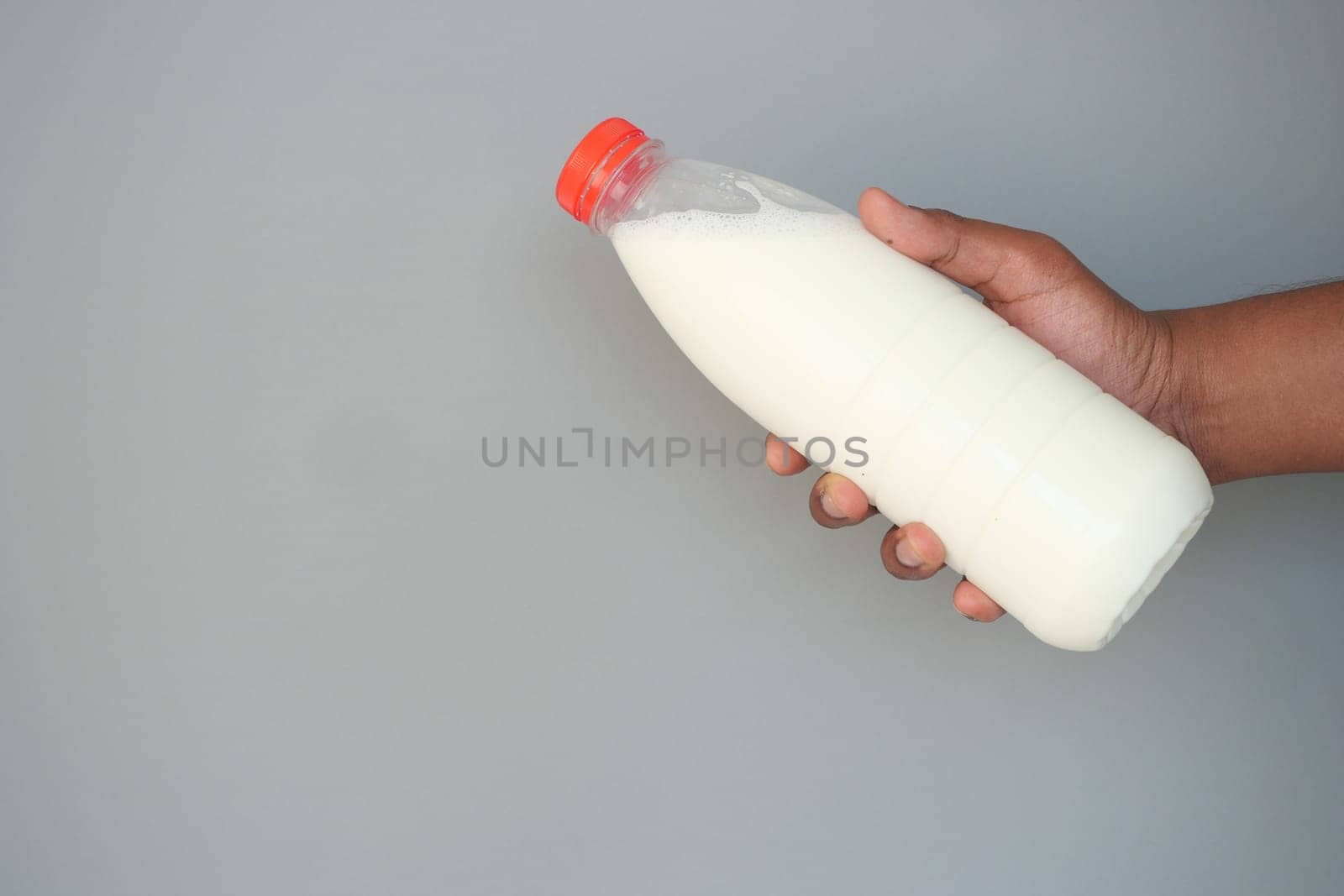 A person holds a clear bottle filled with fresh milk, ready for use.