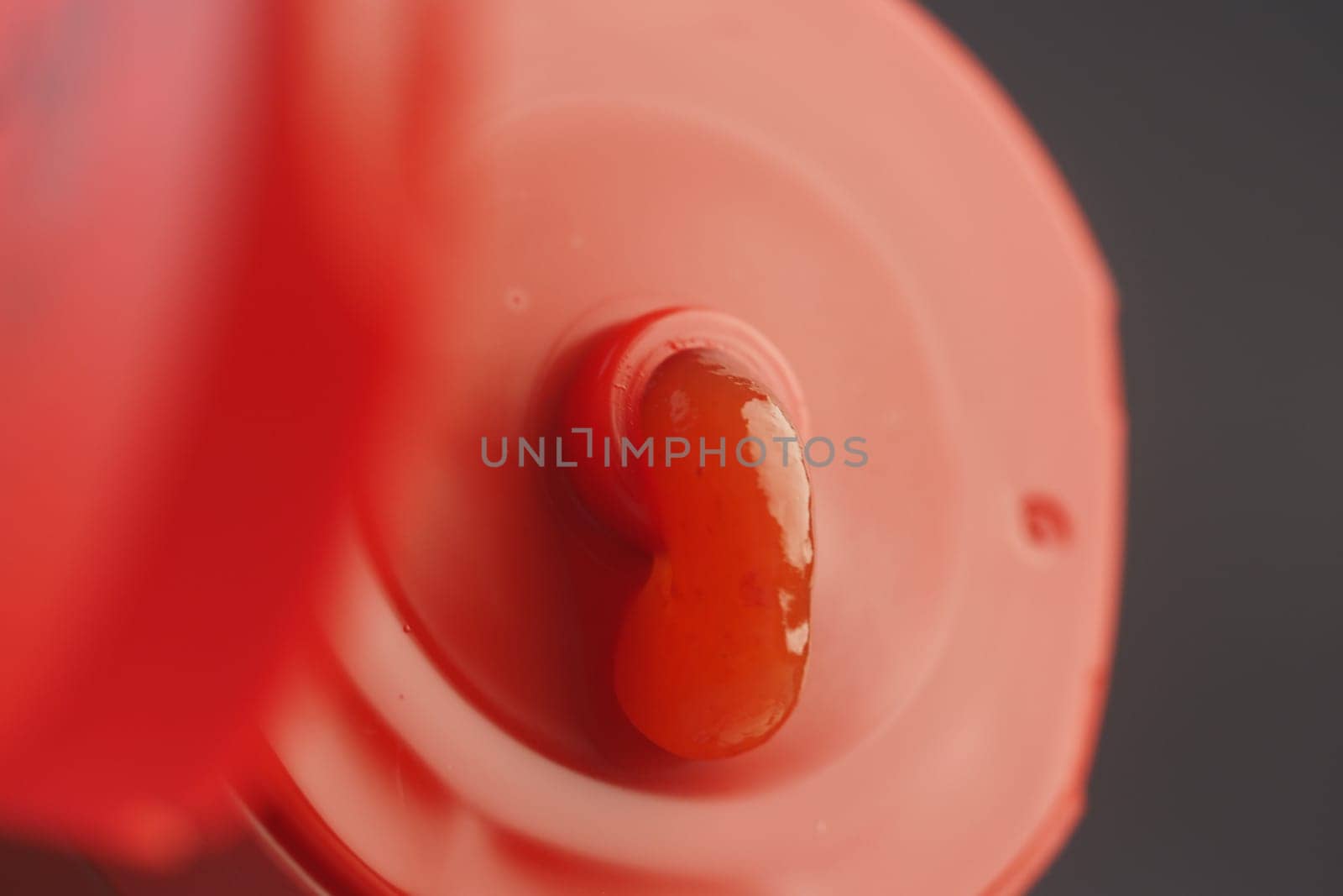 A smooth dollop of bright red sauce rests on a bottle cap.