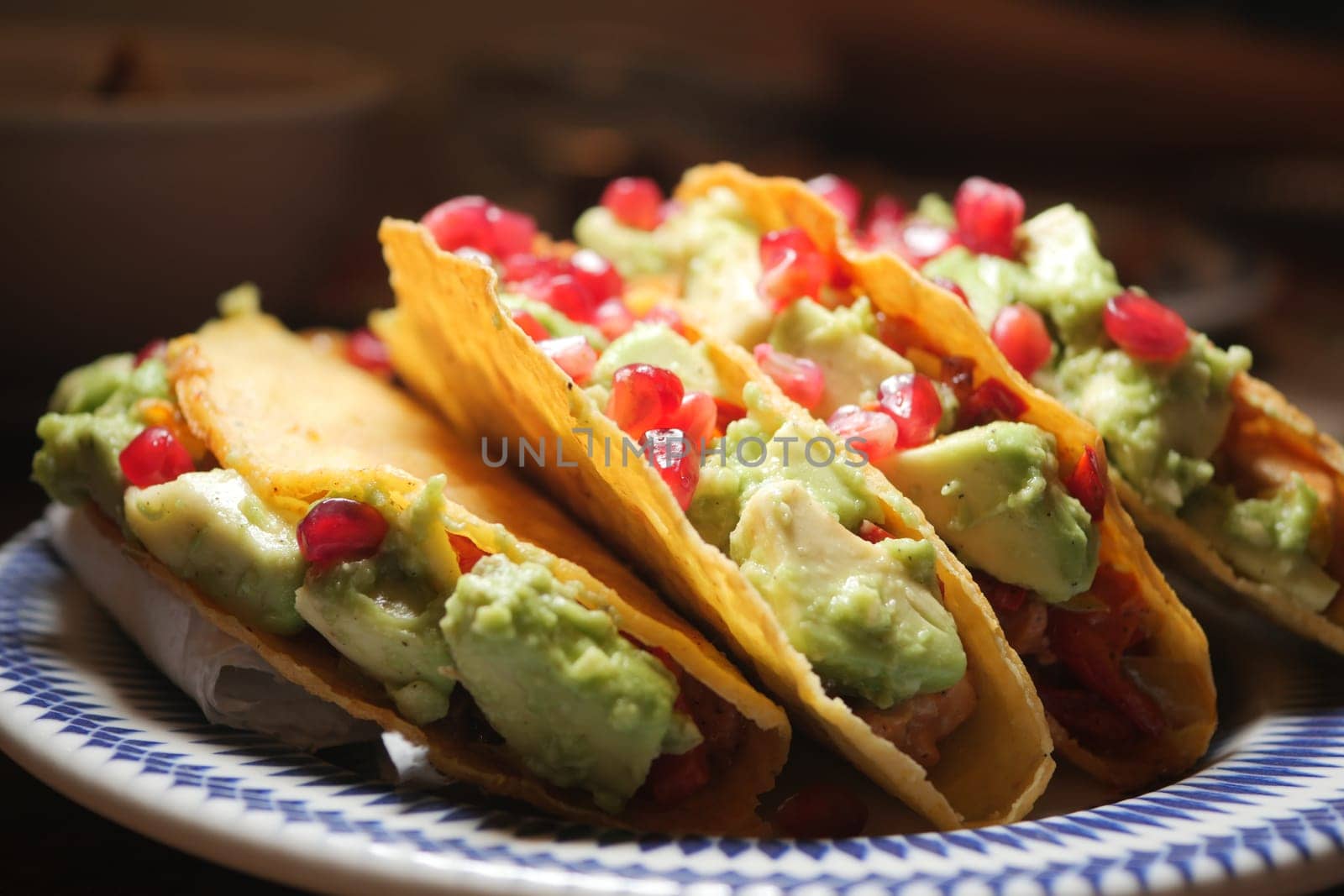 Delicious tacos filled with guacamole and garnished with pomegranate.