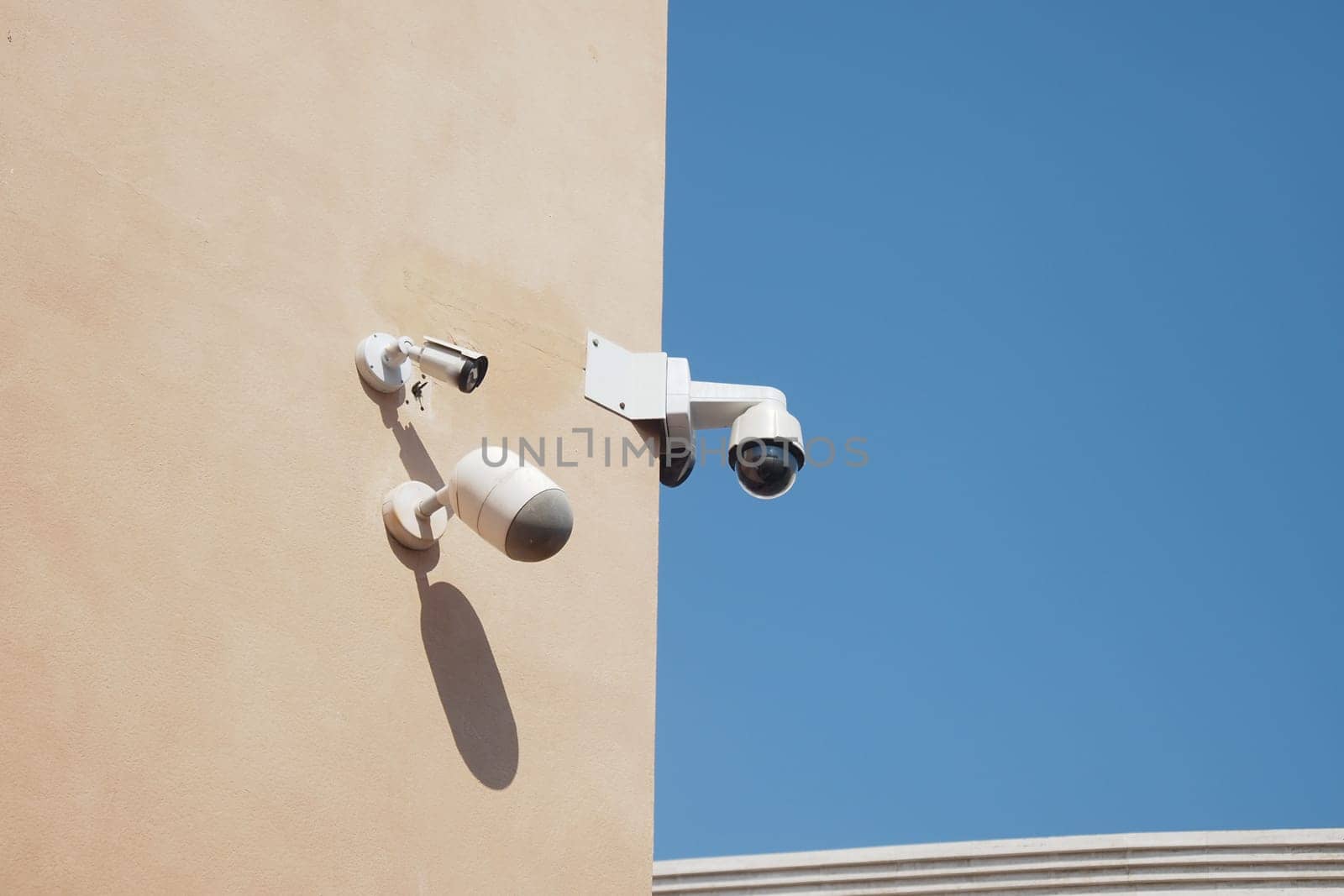 Security cameras observe the area from a building's corner during daytime.