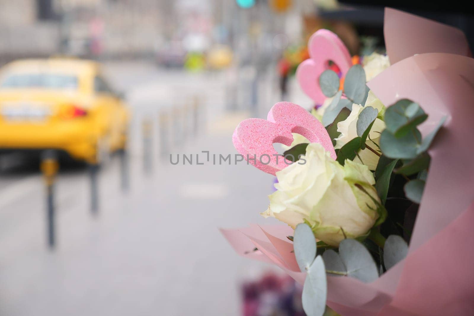 Colorful flowers with heart shapes are displayed on a city sidewalk.