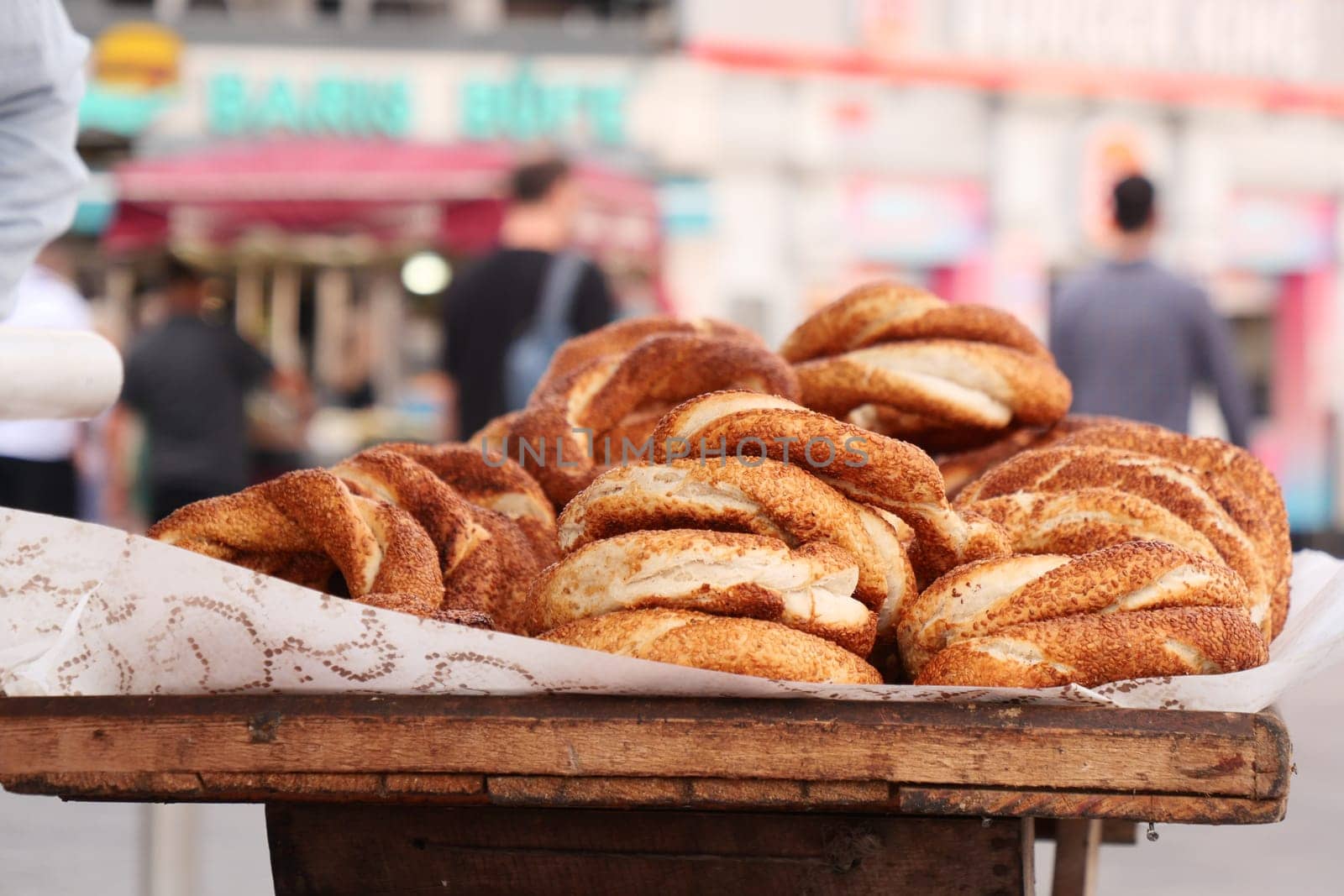 Warm, freshly baked simit rolls are arranged on a wooden cart in a market.