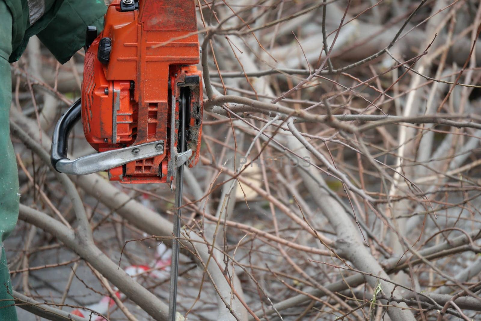 A worker removes debris using a chainsaw during a cleanup effort.