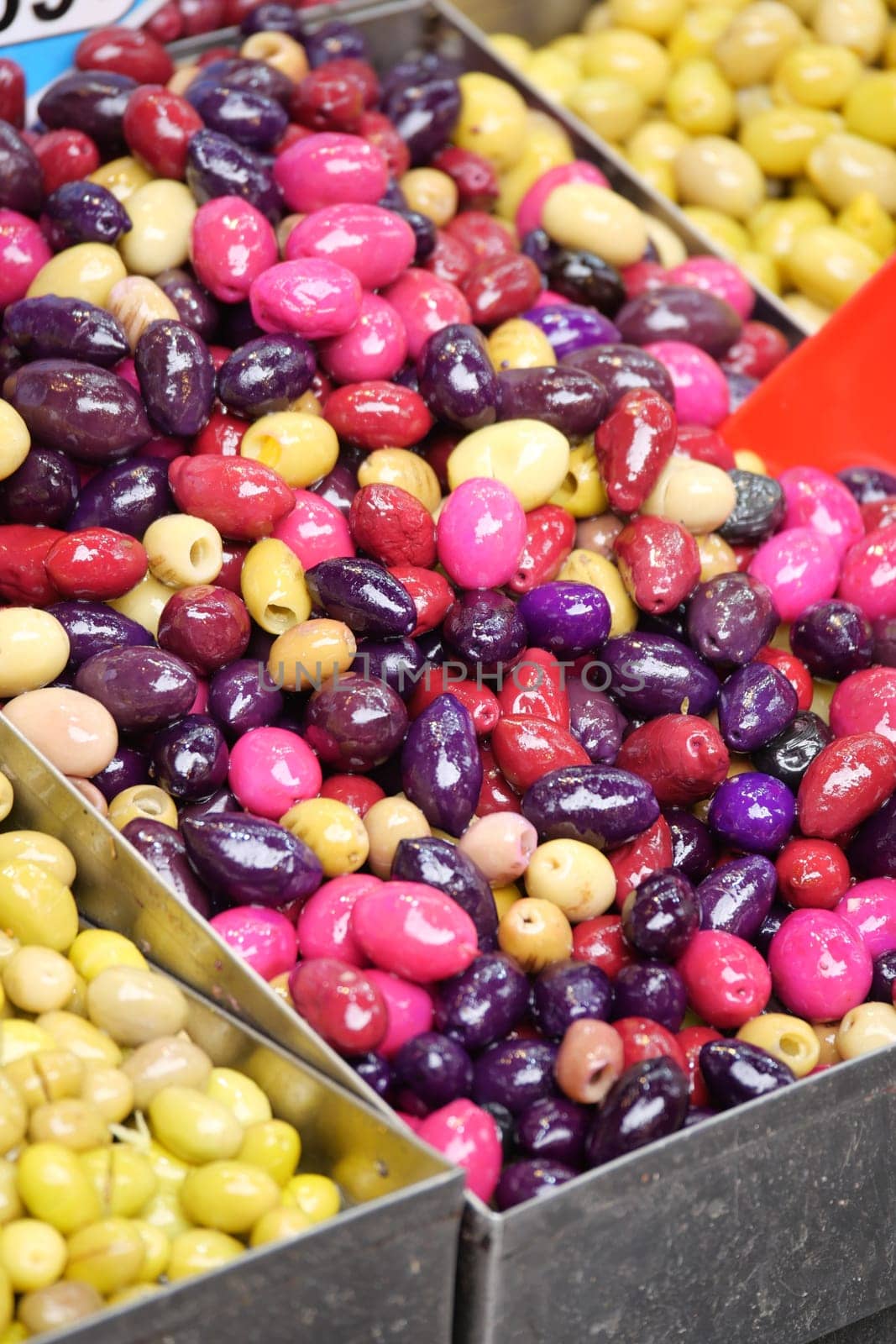 Vibrant selection of olives in various colors arranged in baskets at market.