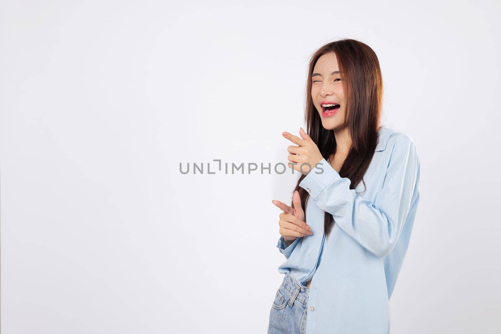 With gesture of what up, woman smiles and points finger like a gun, while another woman gives cheeky expression full of confidence, standing against isolated white background.
