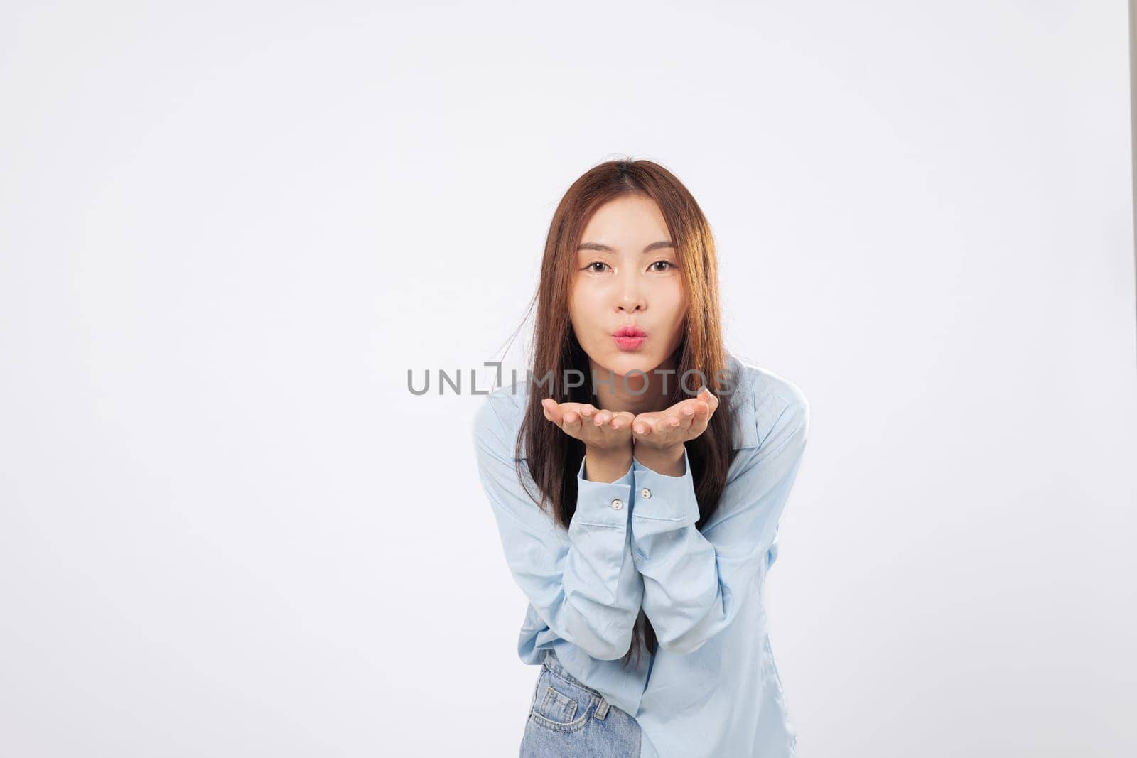 Blowing kiss into the air, happy woman sends love with open palms, another woman smiles gently with hands near mouth, both expressing warmth and affection isolated on white background.
