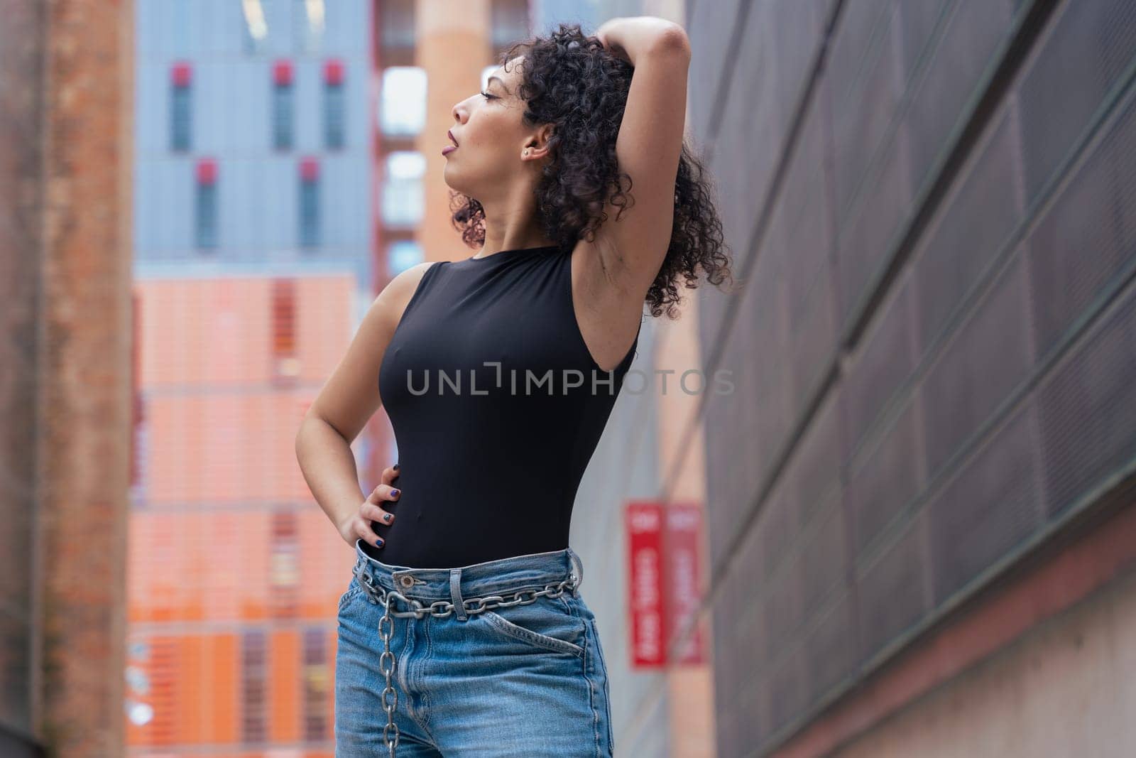 African American woman dancing in a creative pose between benches in an urban setting. She wears casual clothes and shows balance, strength, and expression. Concept of movement, art, and freedom.