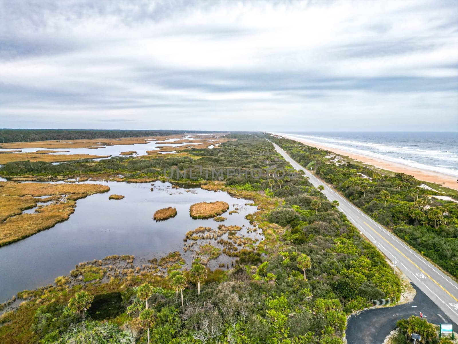 This beautiful stock image showcases a scenic Florida highway, flanked by lush wetlands on one side and the sparkling Atlantic Ocean on the other, emphasizing the region s stunning natural beauty.