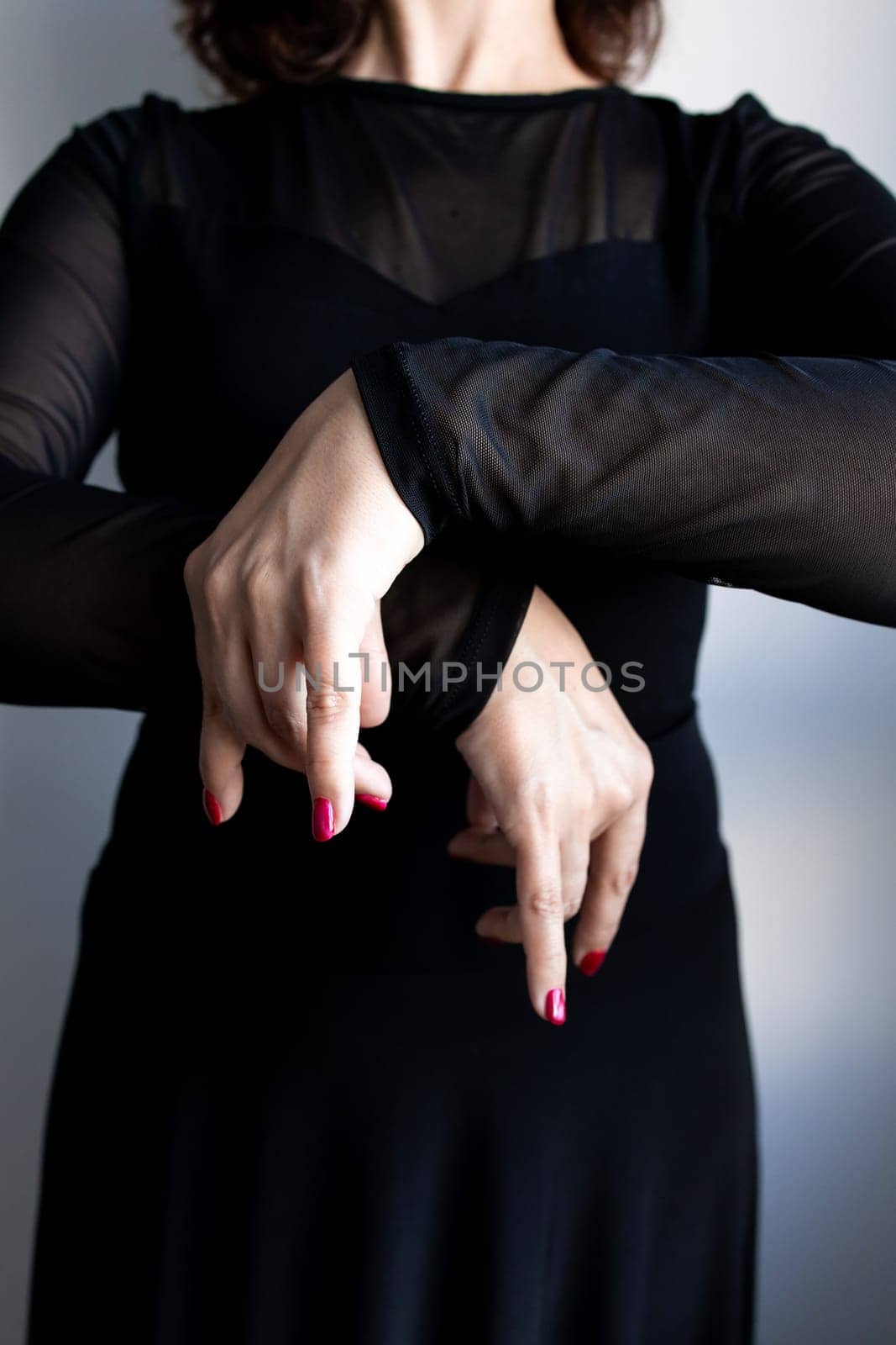 Female adult caucasian in black outfit performing expressive hand gesture.