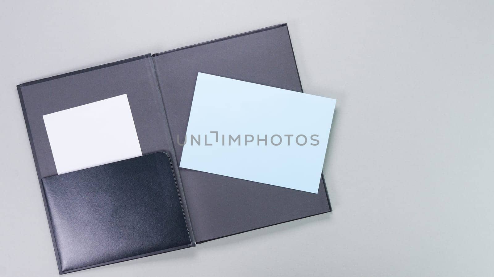 The image showcases an open black leather portfolio cover, elegantly displaying a blue sticky note on the right side, perfect for jotting down quick reminders or important notes.