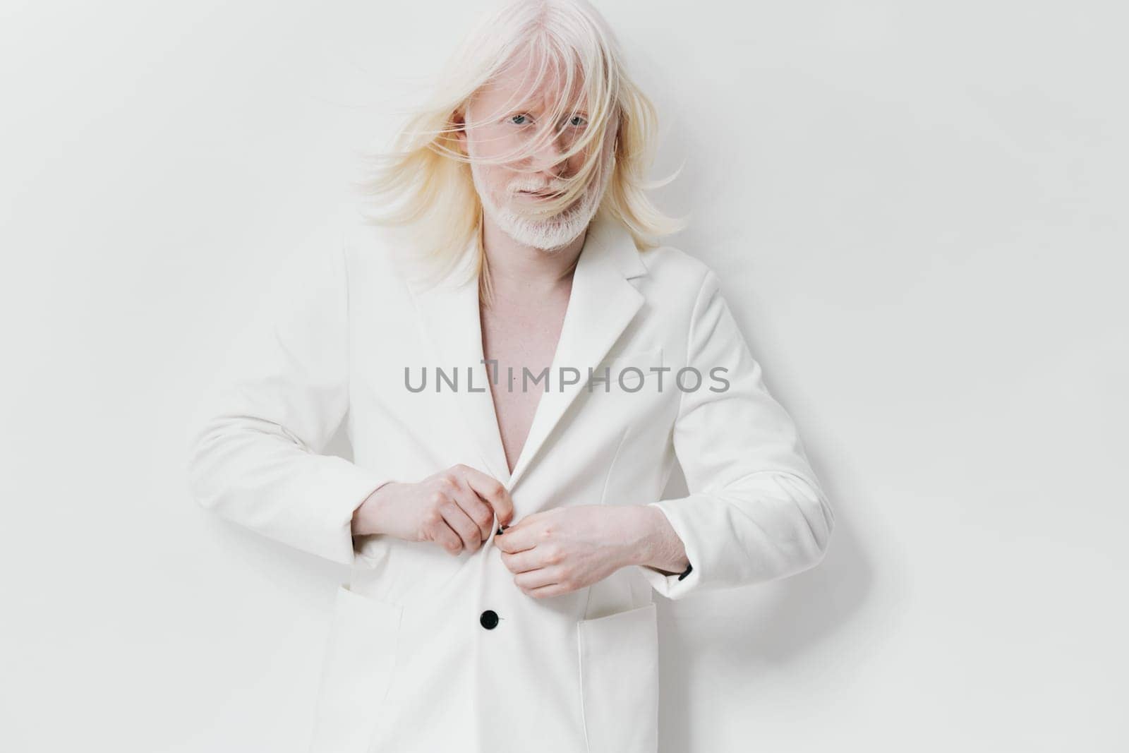 A contemporary model in a sophisticated white blazer is portrayed on a minimalist white background The model s light hair in motion enhances the artistic expression of elegance and modernity in fashion photography