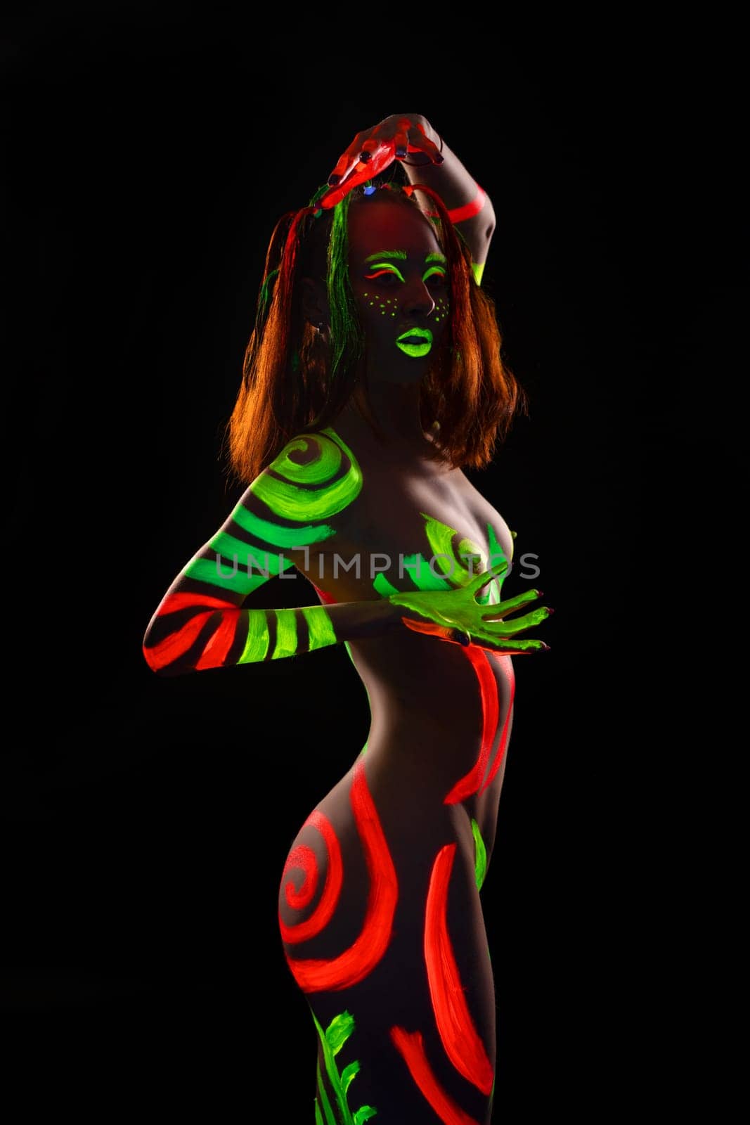Portrait of topless woman with UV bodyart dance in dark