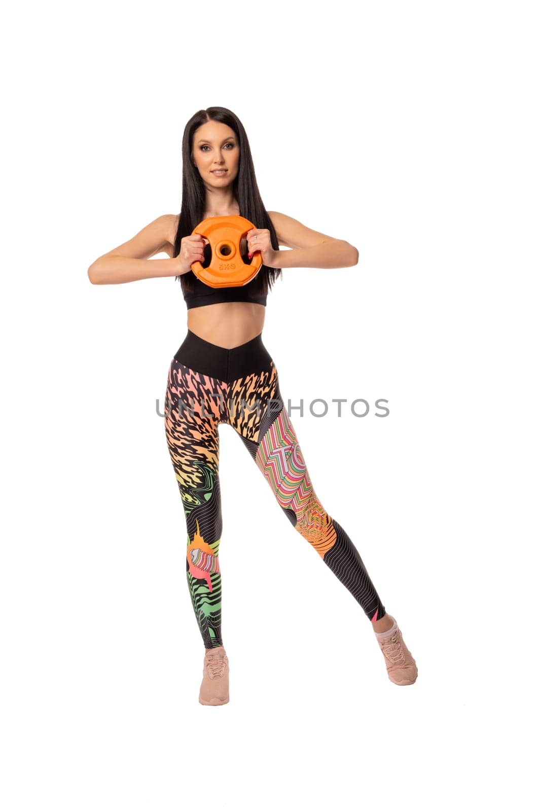 Full body of confident young female in trendy outfit looking at camera while standing on white background in studio