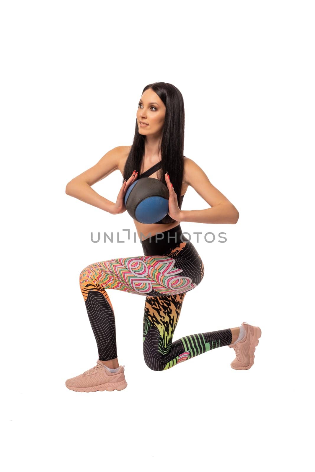 Full body side view of young fit female in sportswear and headphones stretching arms and looking at camera against white background