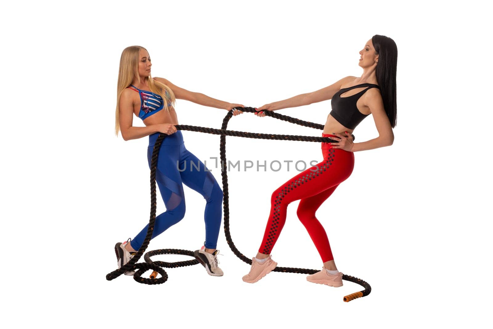 Full body side view of fit female athlete in sportswear and safety harness smiling and looking away against white background