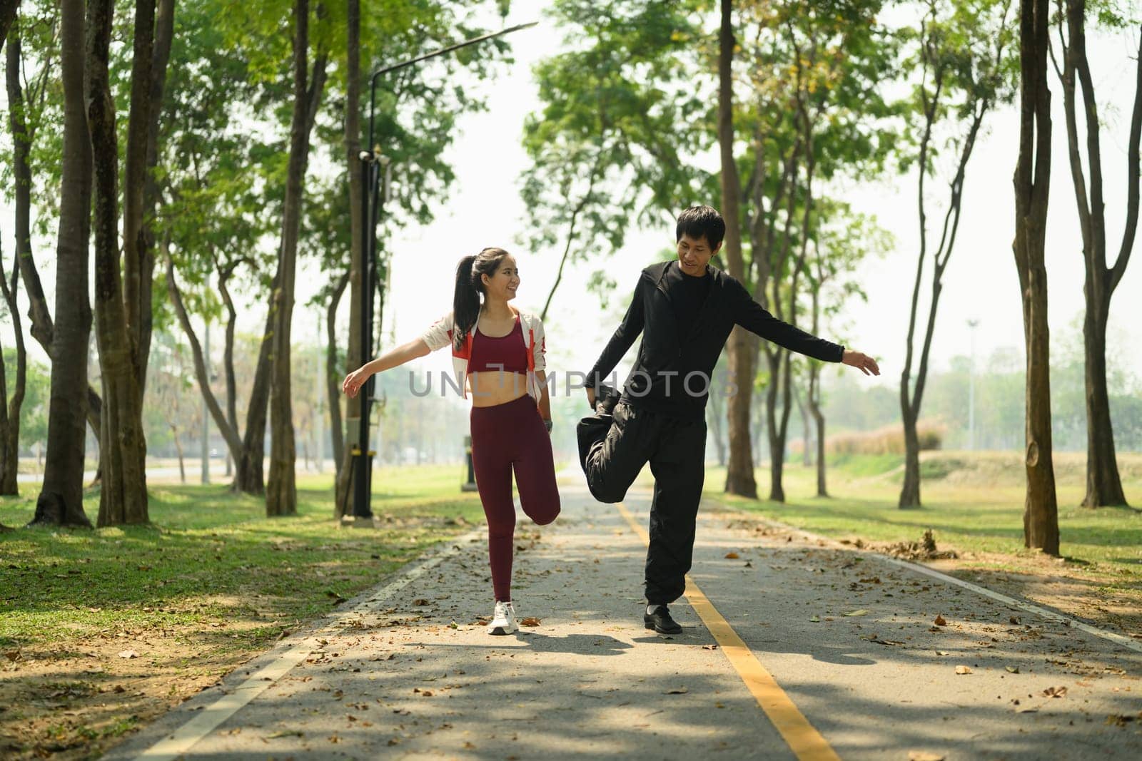 Active young couple stretching before workout in the park.