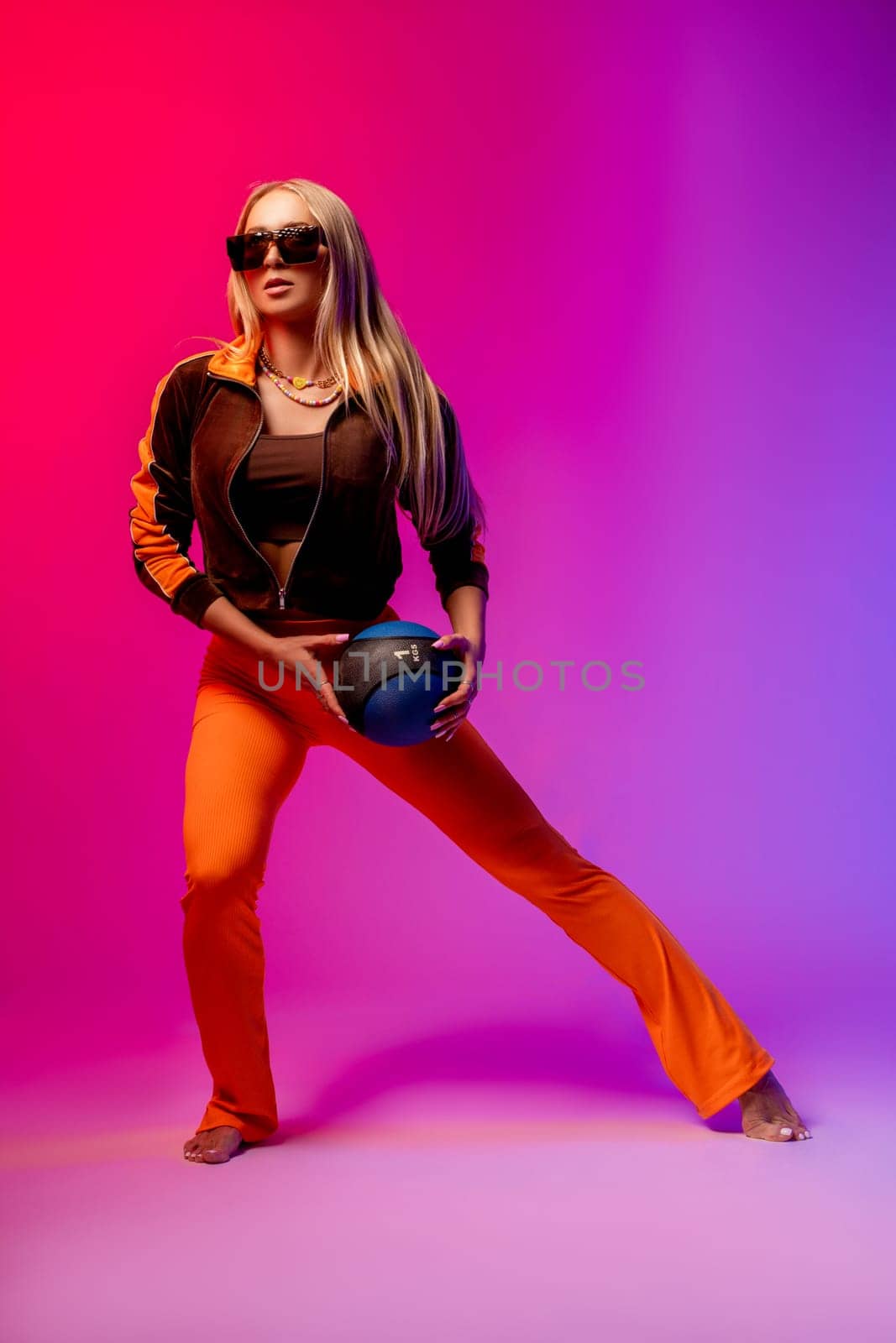 Full body of confident young female in trendy outfit and sunglasses standing against pink background