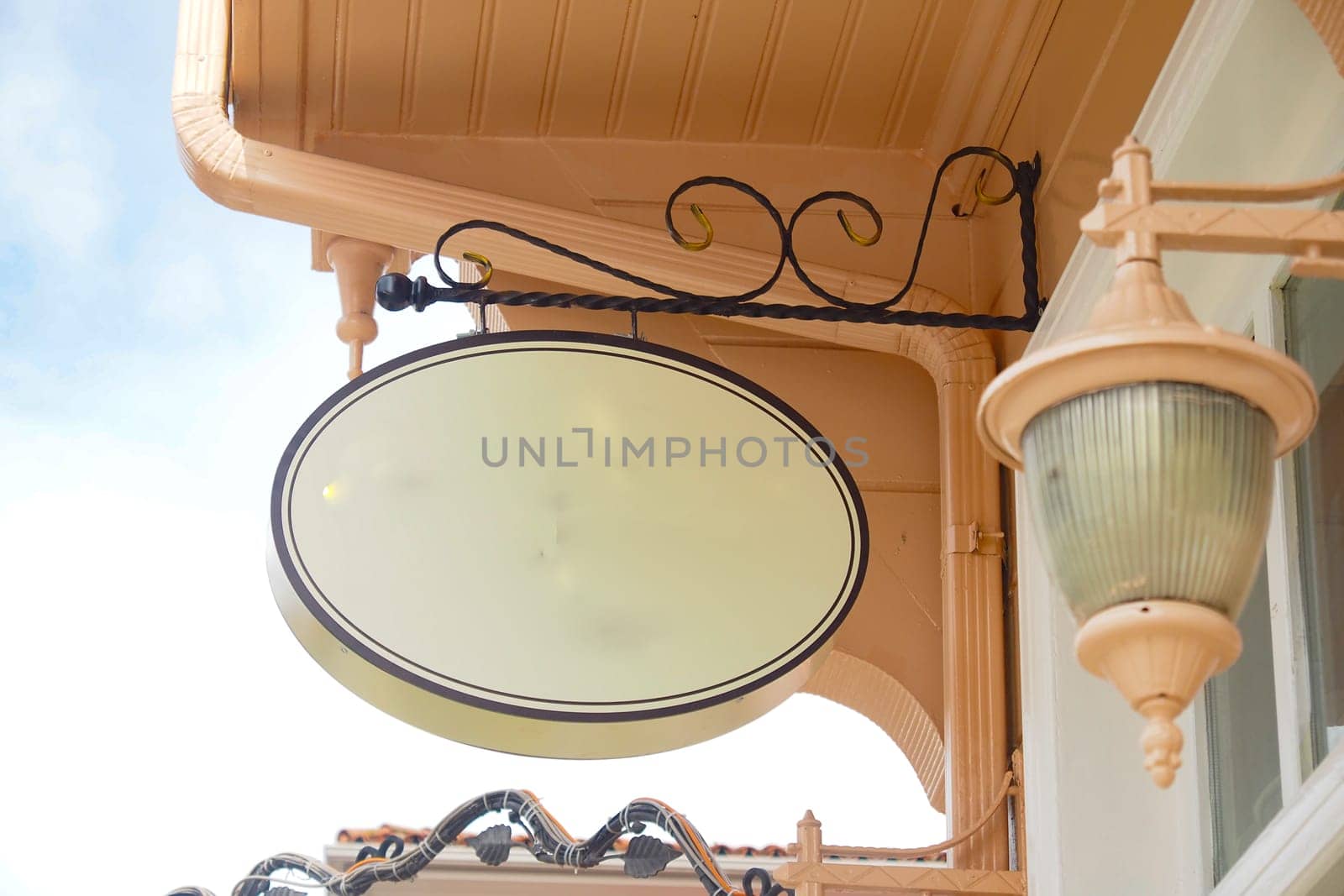 A charming sign hangs from a lovely building under blue skies.