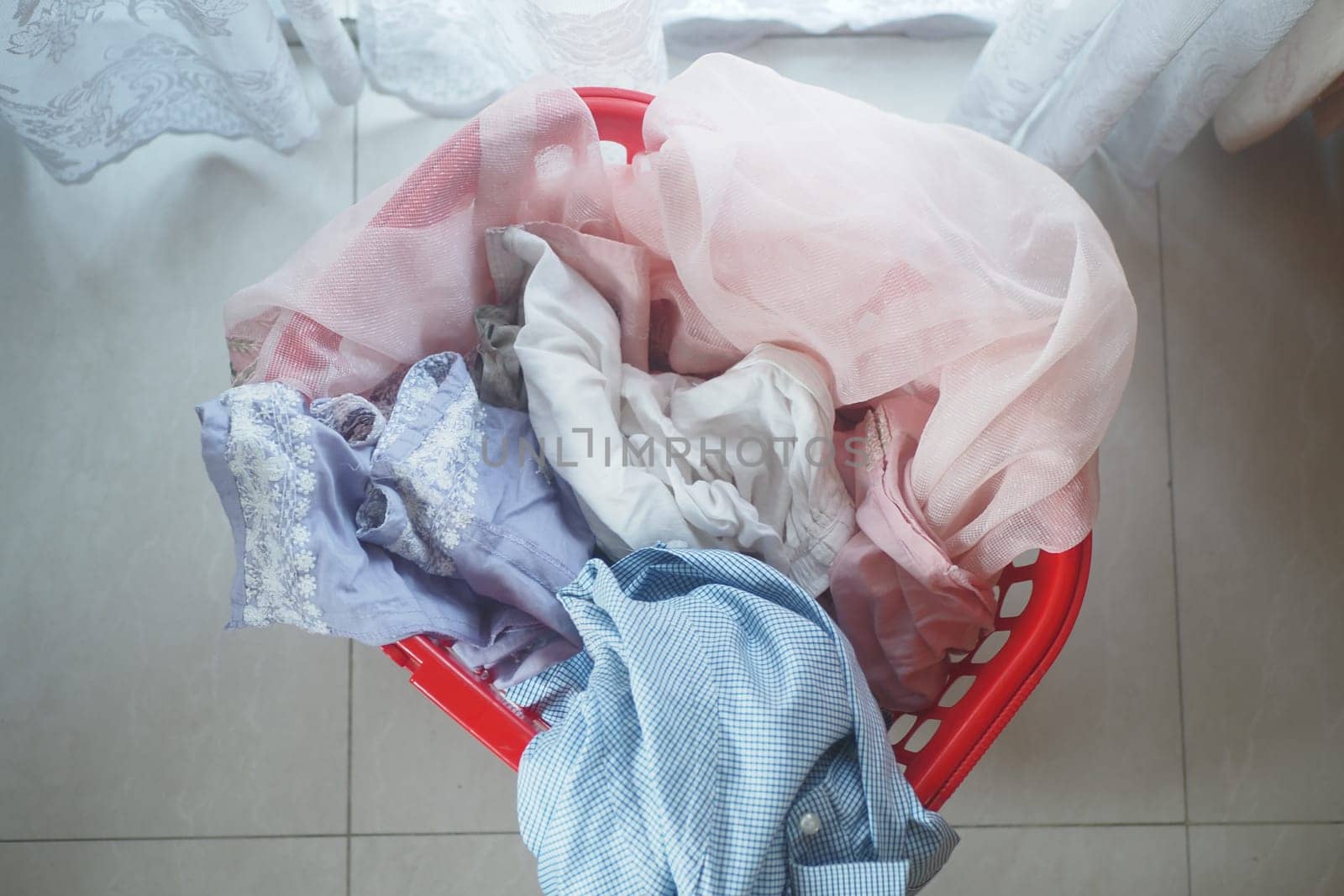 A bright basket holds various clothing items waiting to be washed.