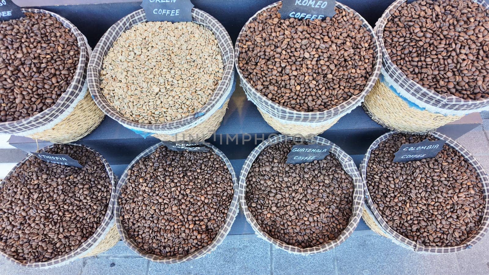 Multiple baskets filled with various coffee bean types showcased outdoors.