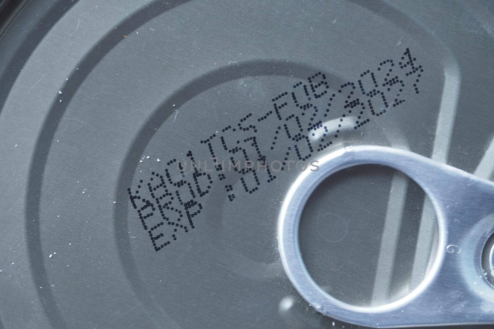 Inspecting the expiry date and production code on a canned food product.