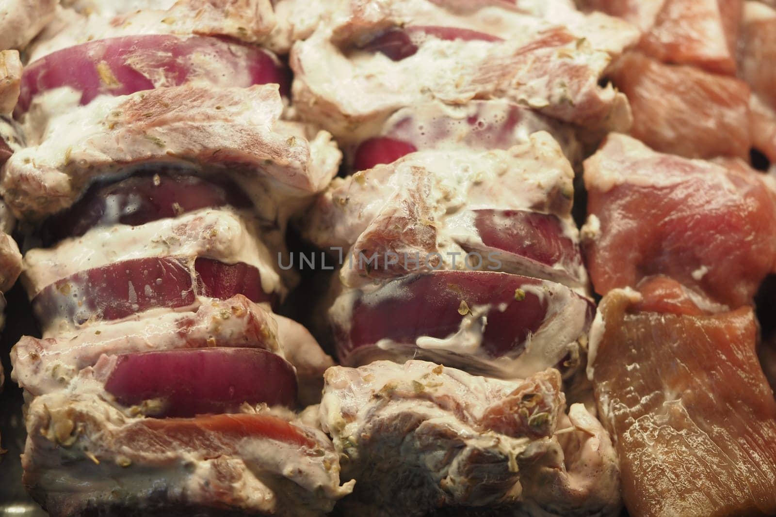 Juicy meat and onion skewers ready for grilling outdoors during summer.