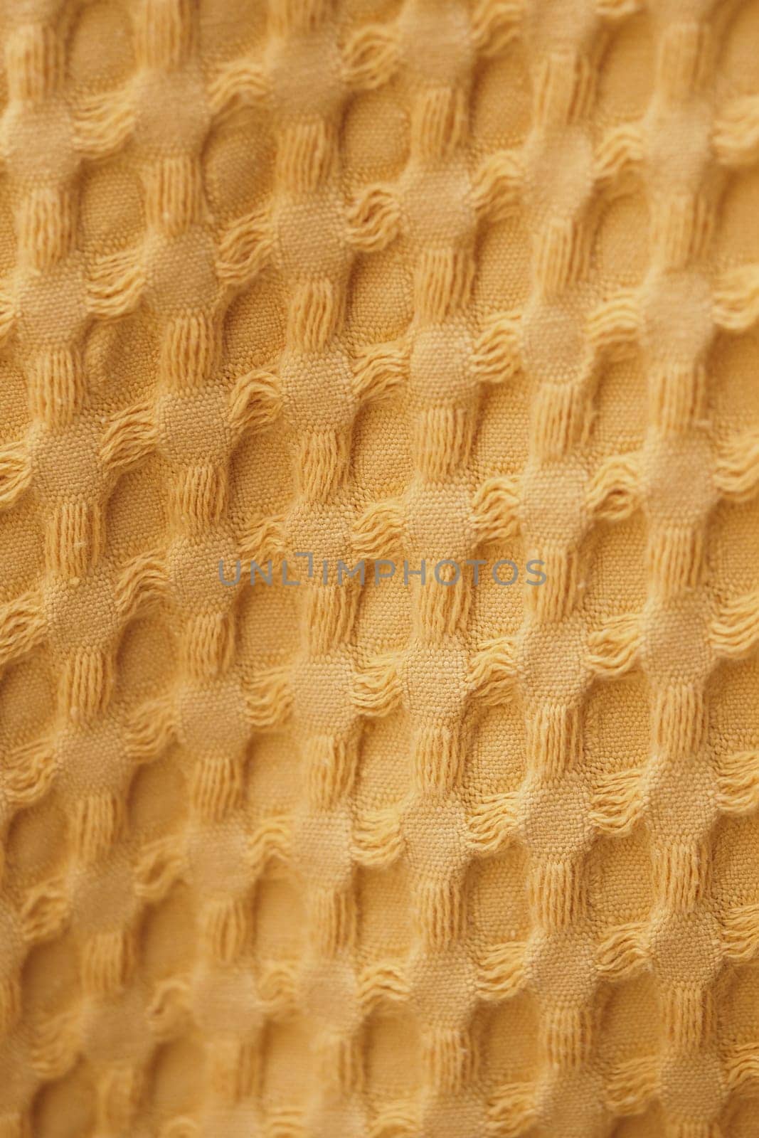 A close-up view of a warm yellow fabric featuring a distinct honeycomb texture.