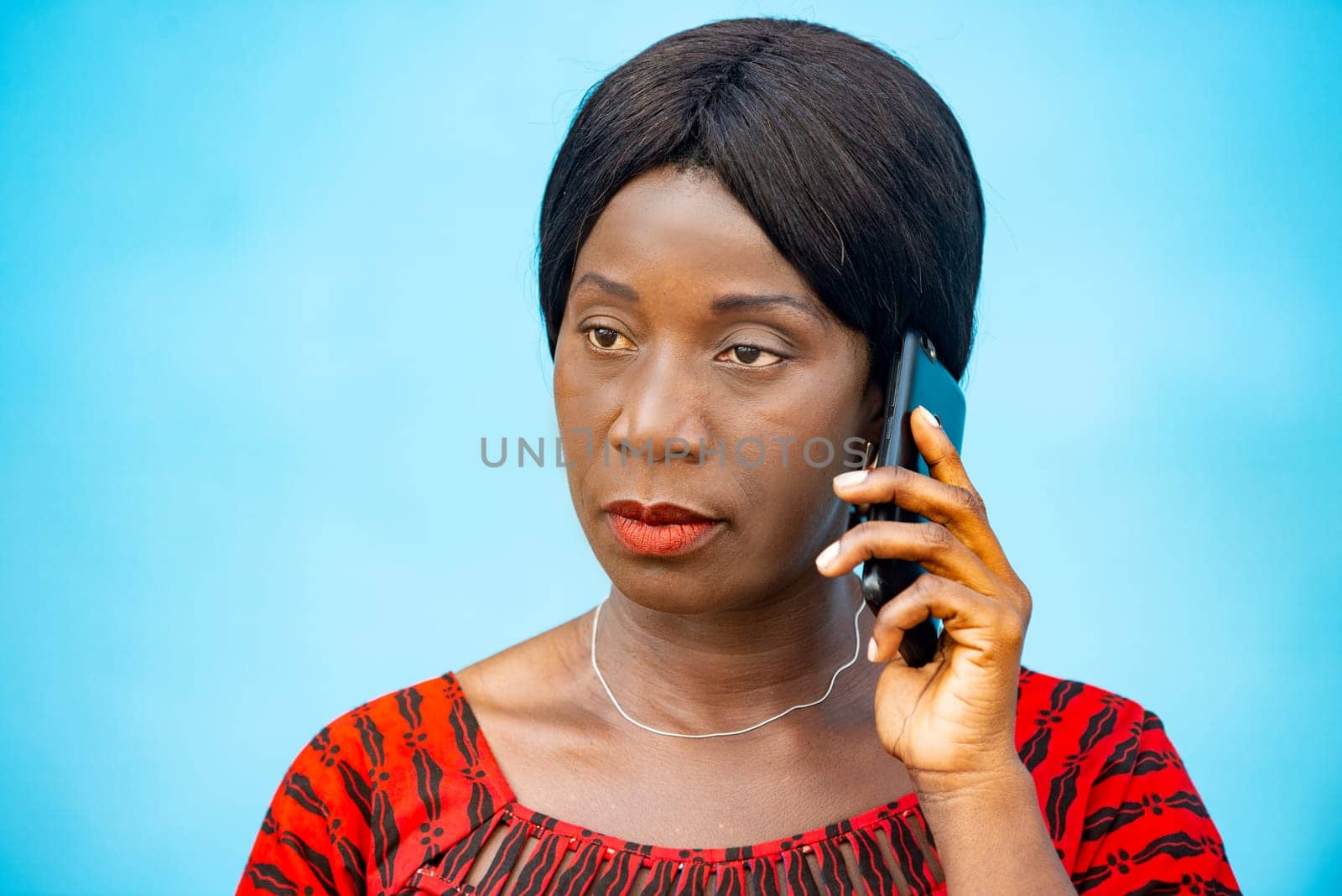 mature woman standing on blue background communicating on cellphone.