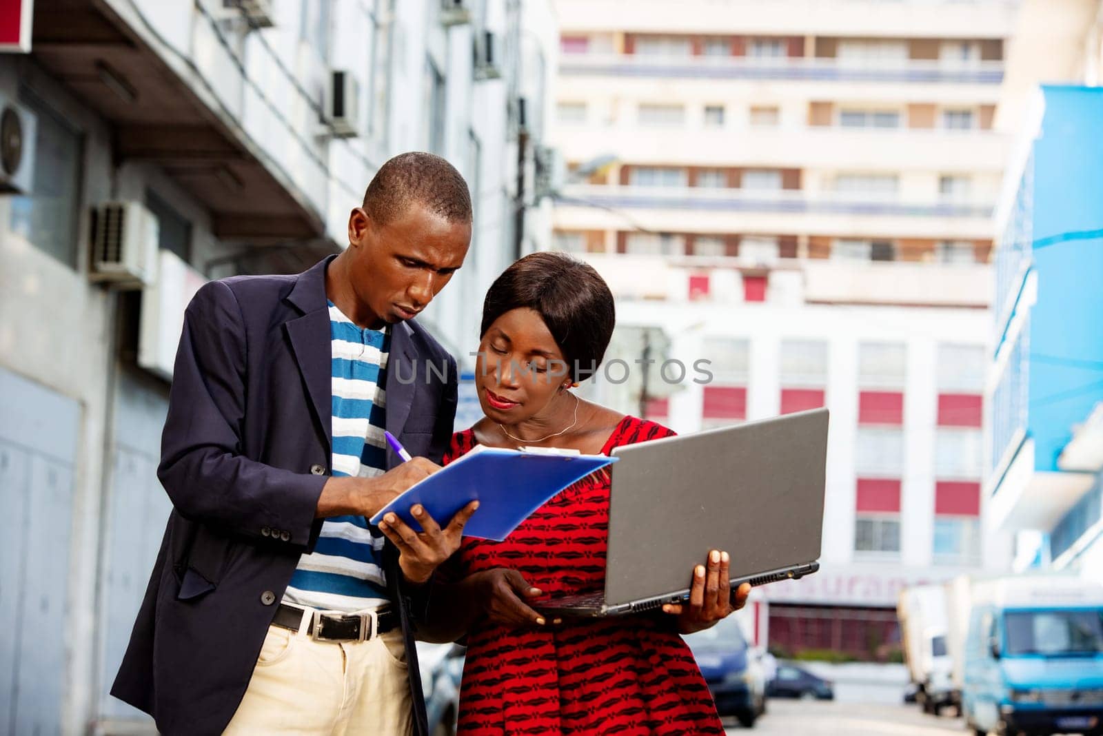 Confident african businessman pointing at a document explaining, the specific project has his assistant on the street while smiling