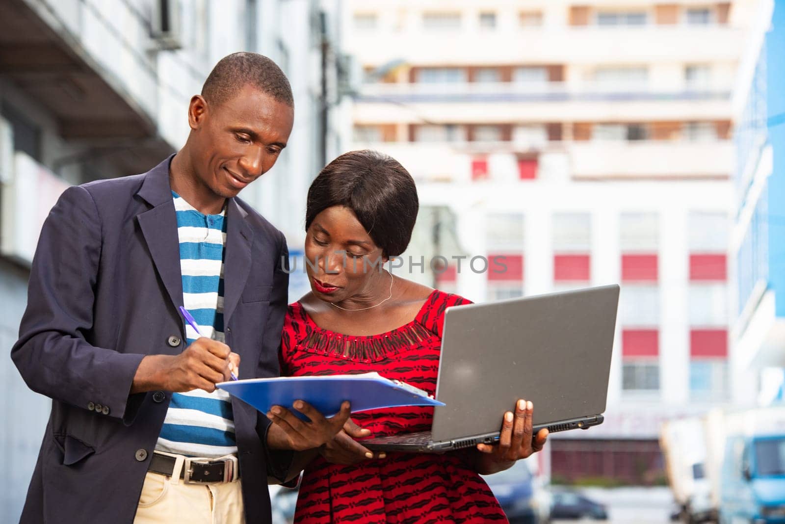 Confident african businessman pointing at a document explaining, the specific project has his assistant on the street while smiling