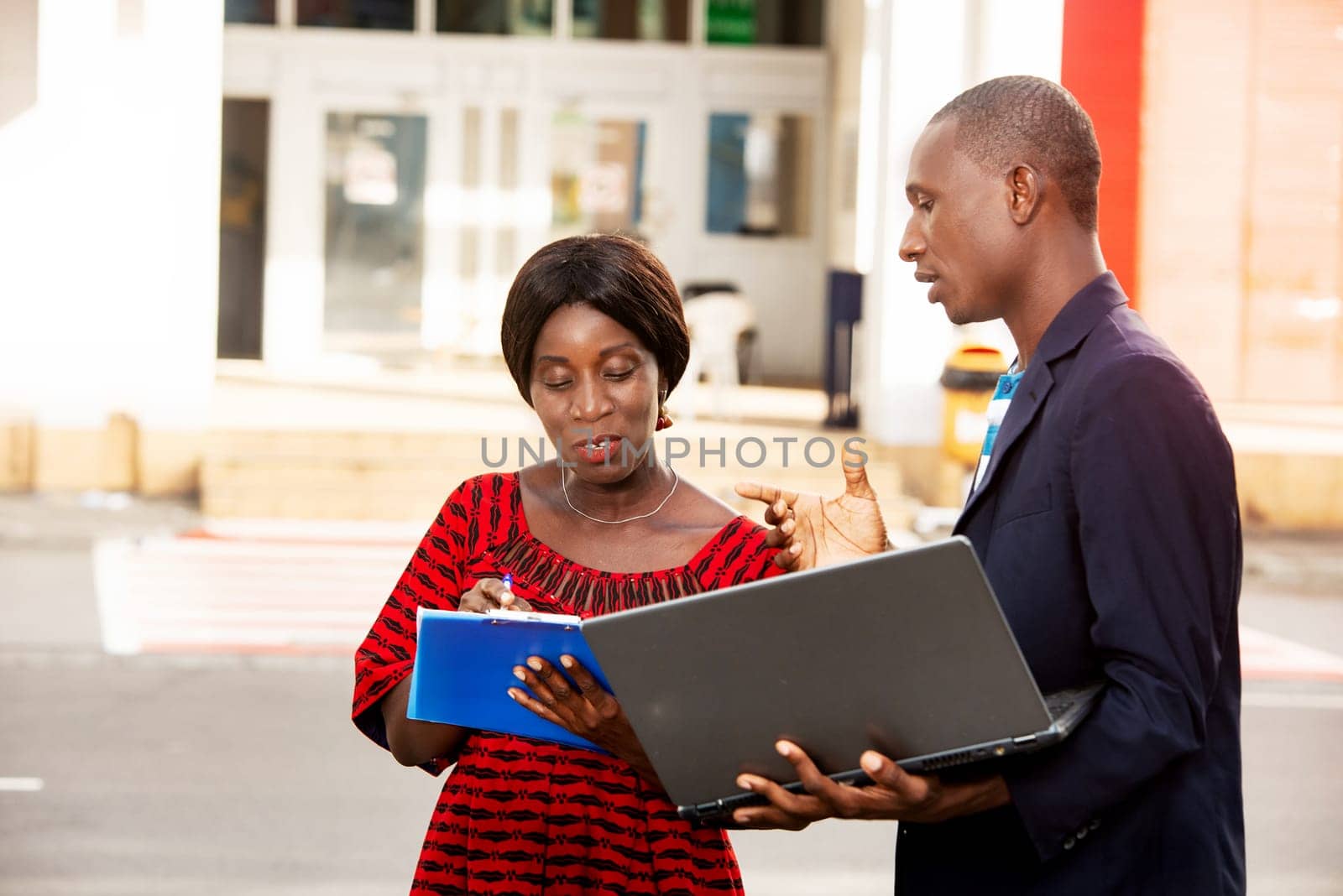 African businessman giving instructions to a beautiful adult woman working on a project in the street