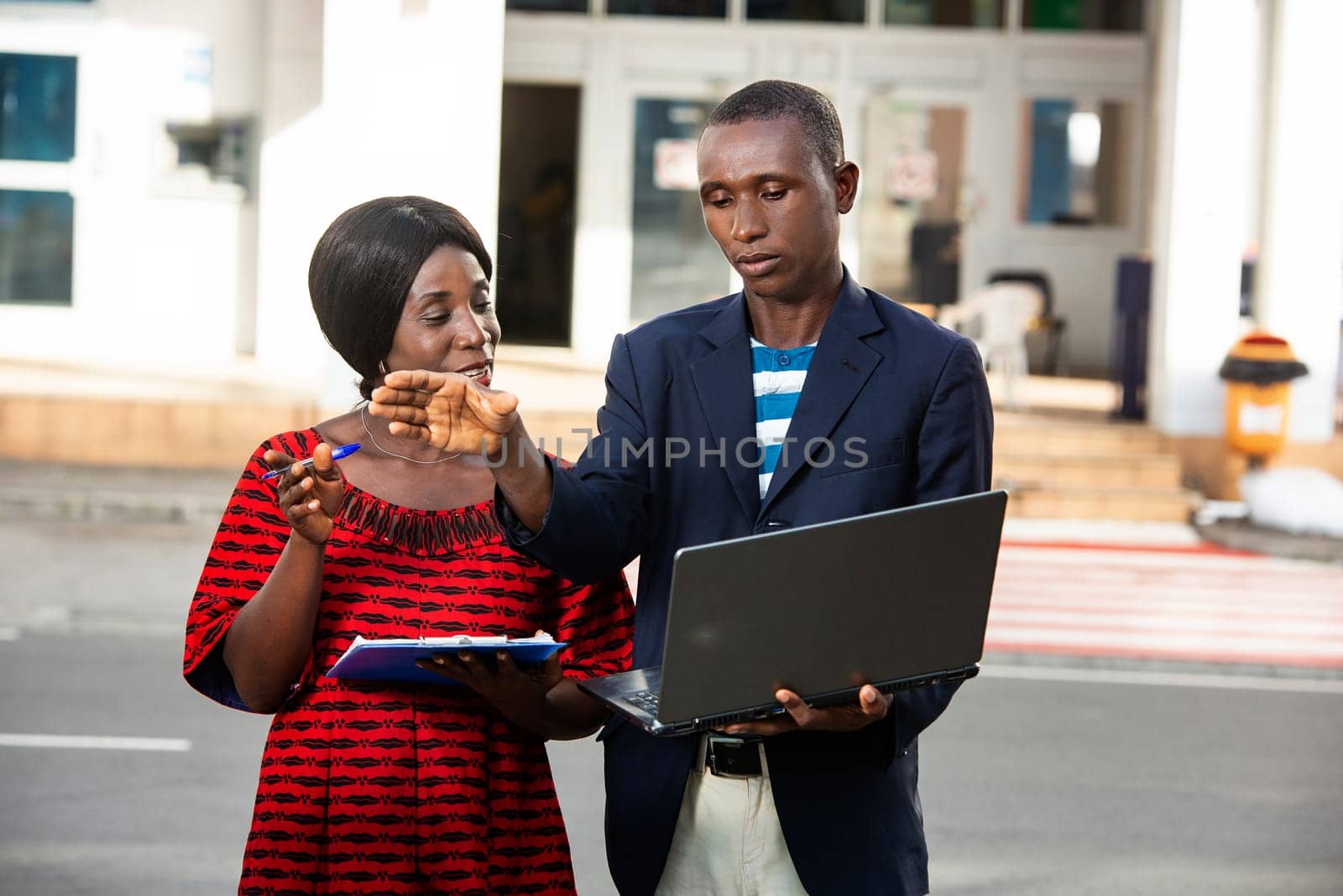 man and a beautiful adult woman as business partners discussing business holding computer and folder on the outside