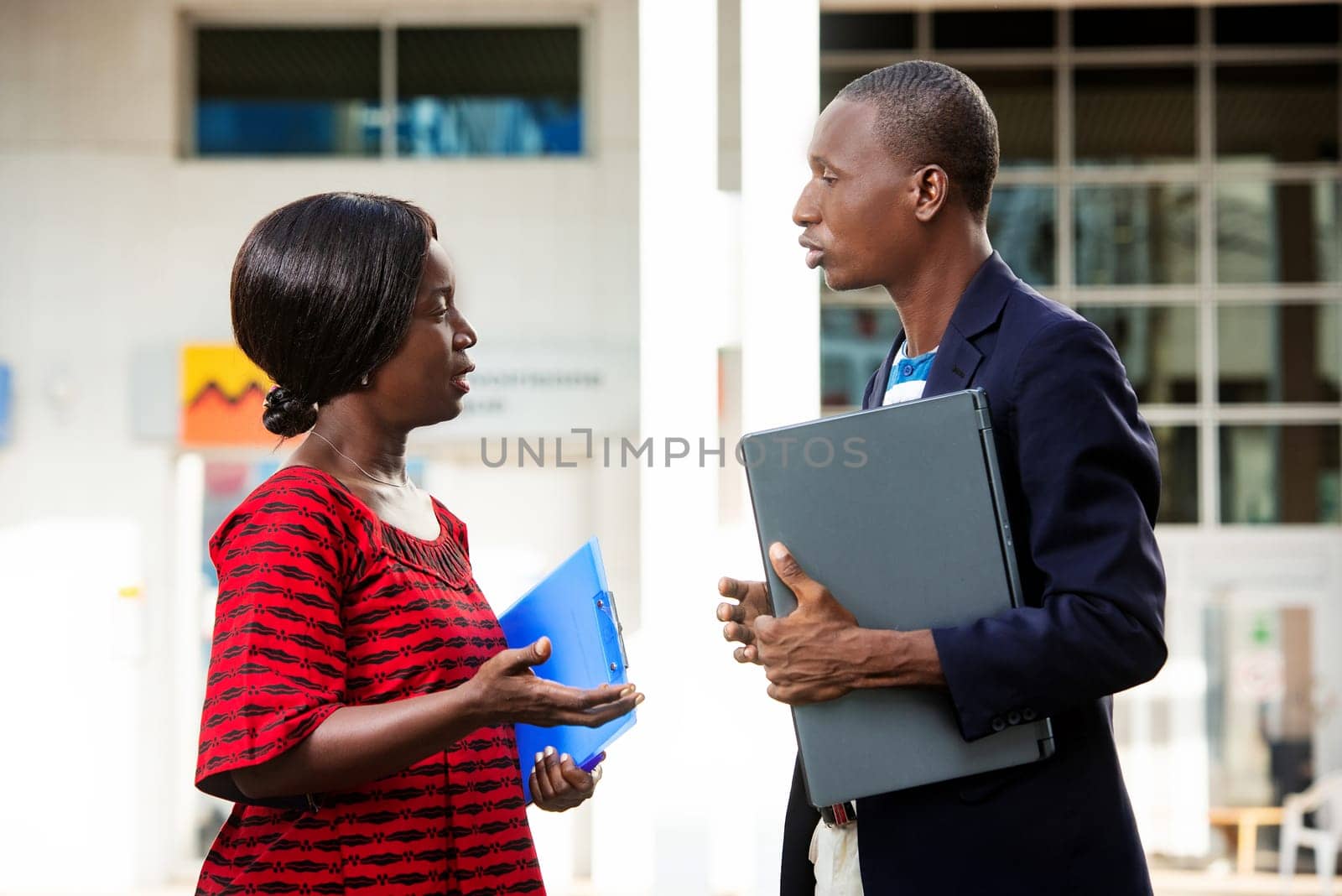 man and a beautiful adult woman as business partners discussing business holding computer and folder on the outside