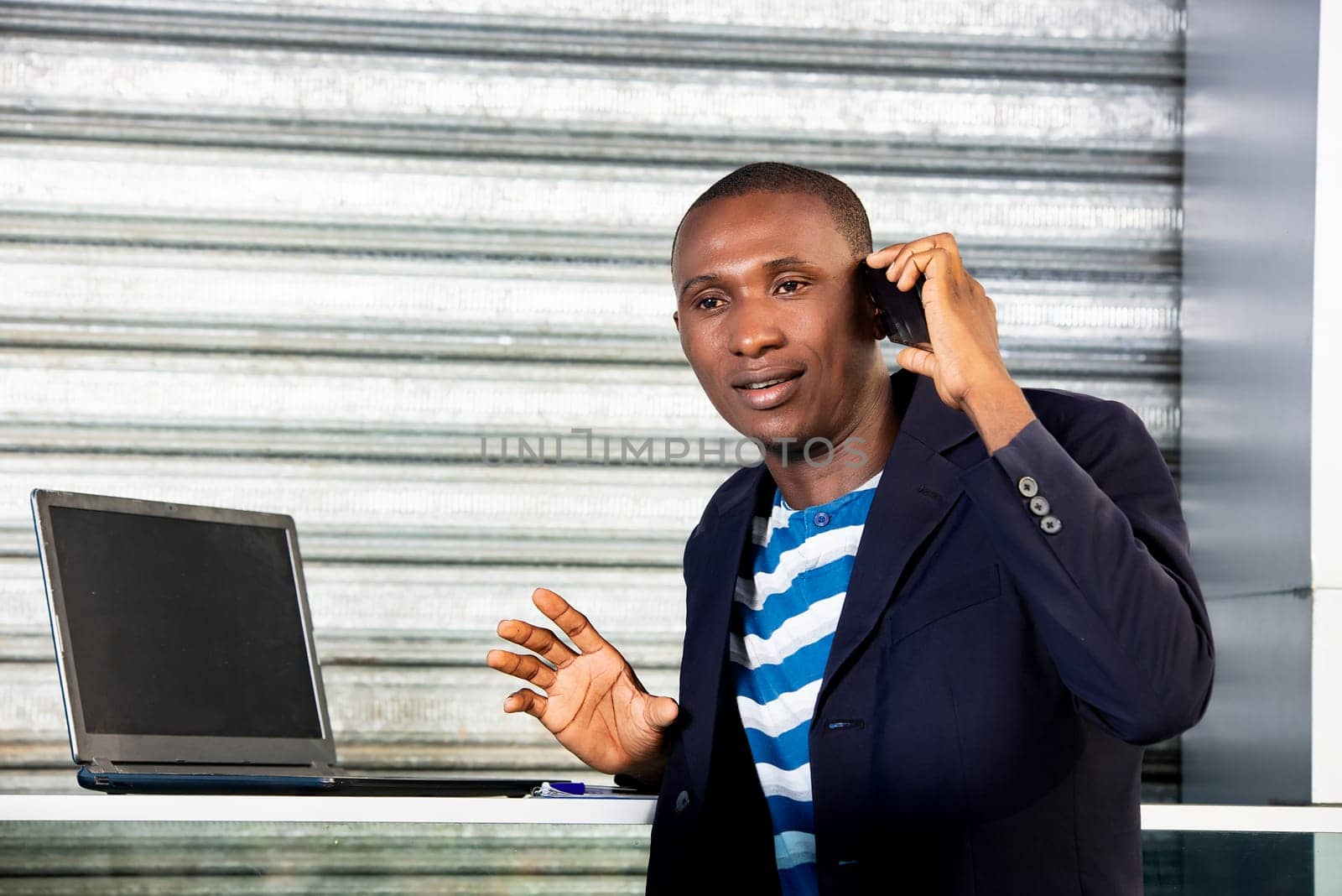 Happy professional african adult business man using a cell phone talking on the phone and smiling in the city center