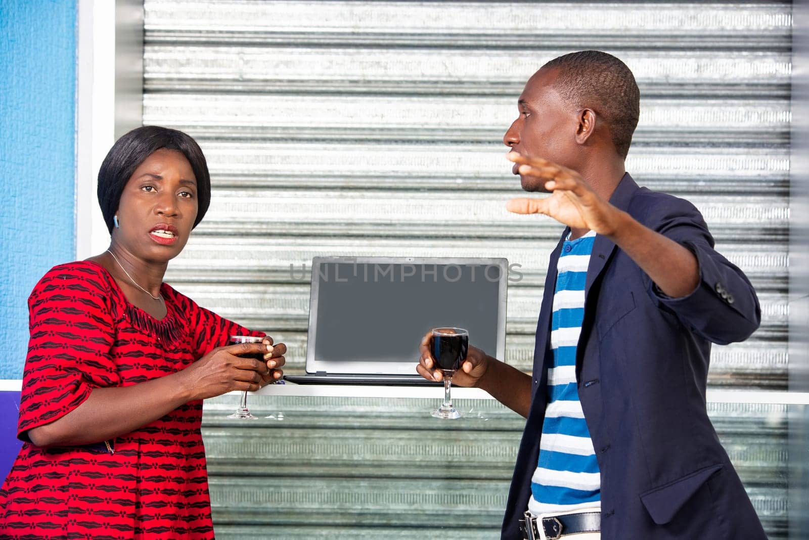 handsome adult businessman and african businesswoman holding a glass of red wine in hand, and looking at the camera