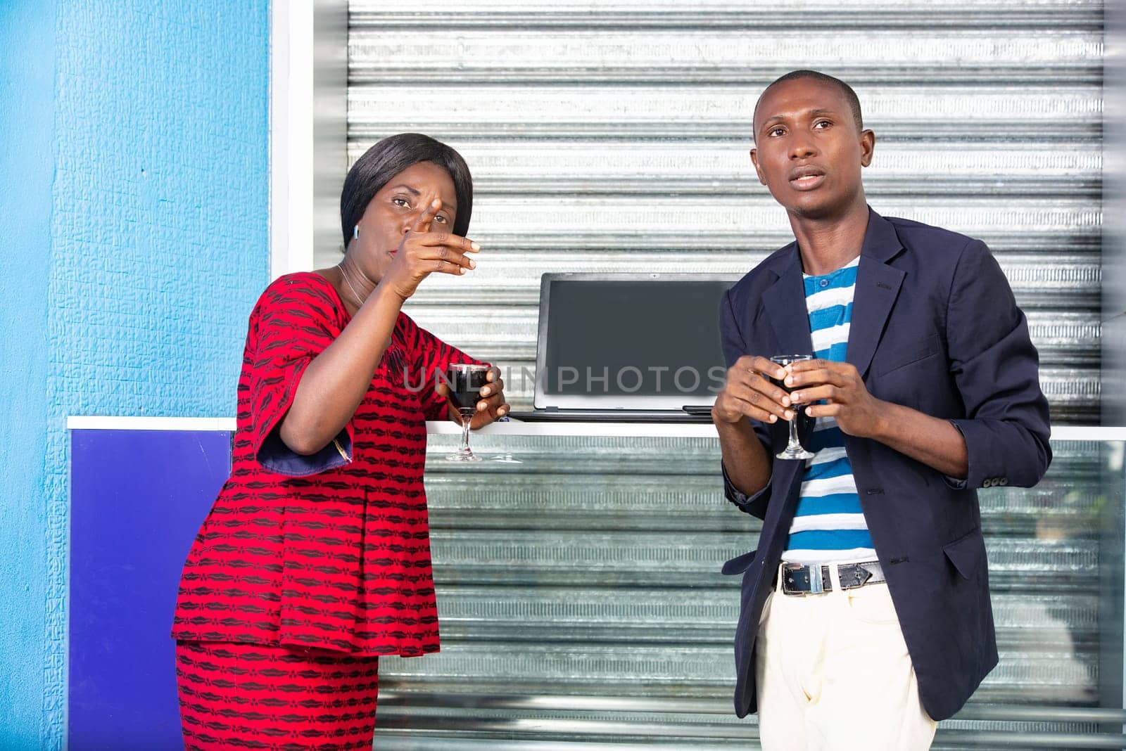 handsome adult businessman and african businesswoman celebrating a win by holding a glass of red wine by hand in the street