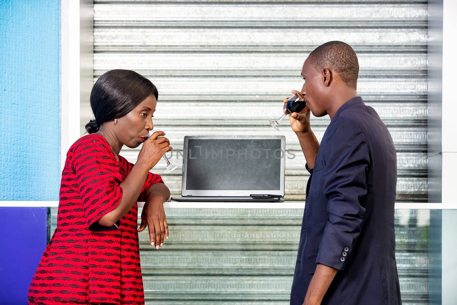 handsome adult businessman and african businesswoman celebrating a victory by drinking a glass of red wine on the street