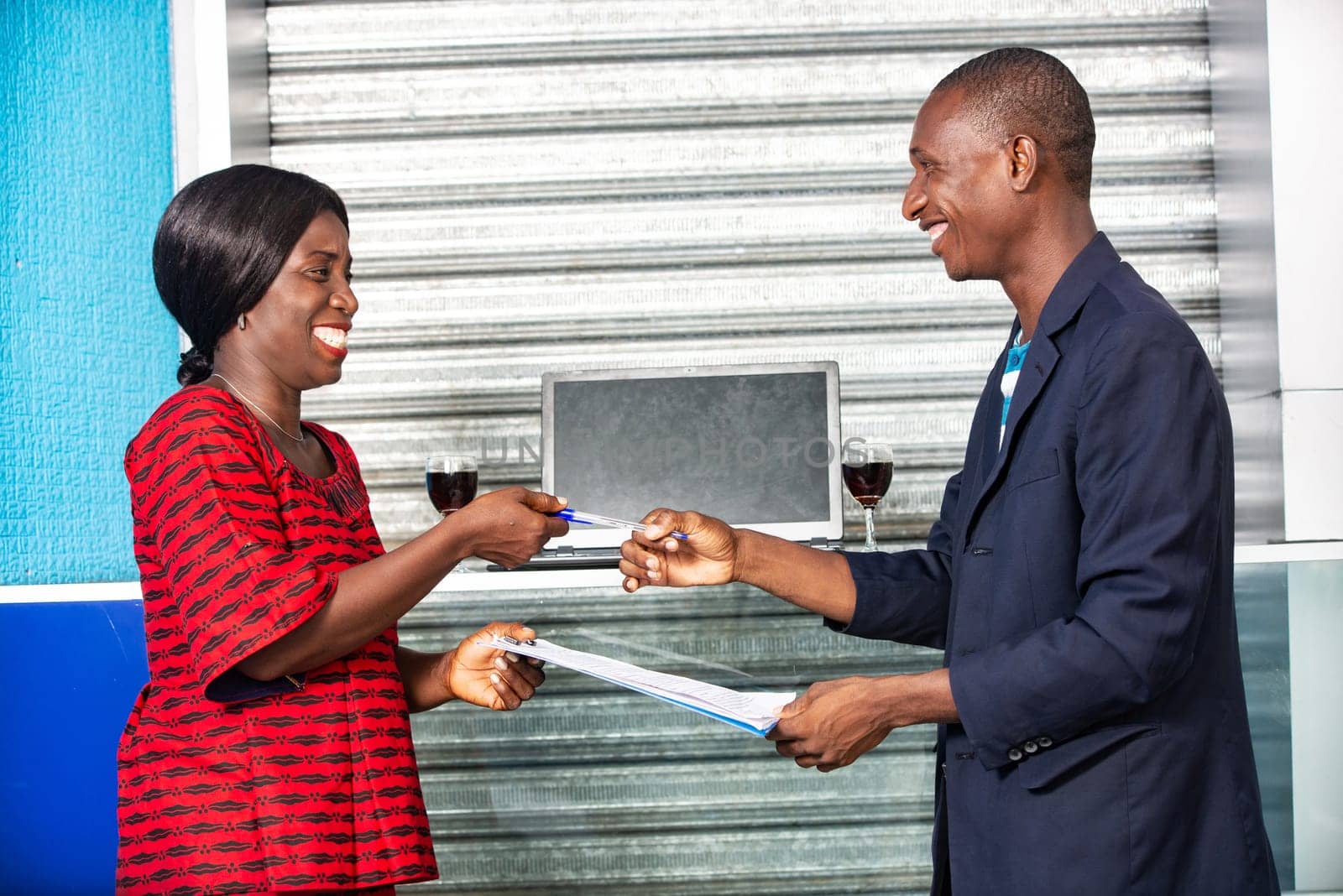 beautiful business women giving a pen to the businessman for signing the contract while being smiling in the street