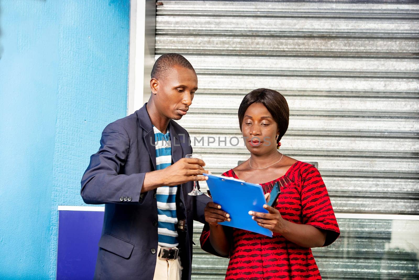handsome african businessman and businesswoman looking at a document outdoors together