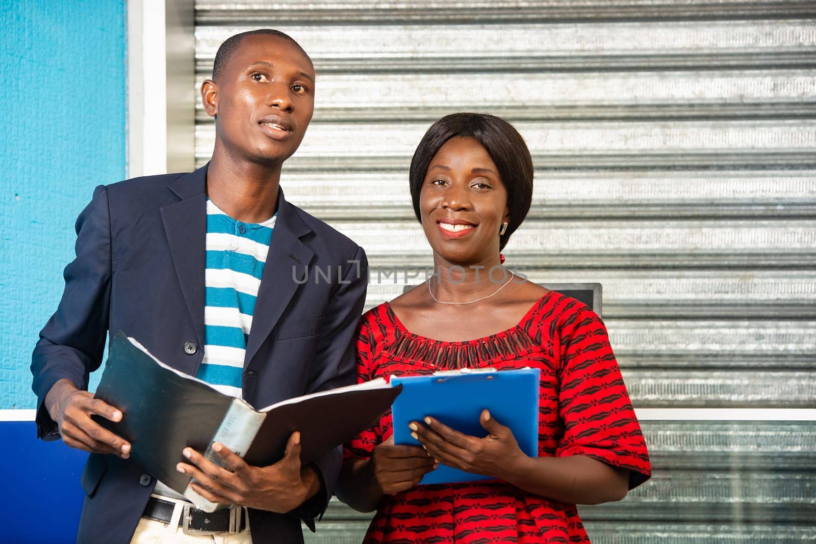 handsome businessman and businesswoman each holding a document outdoors smiling