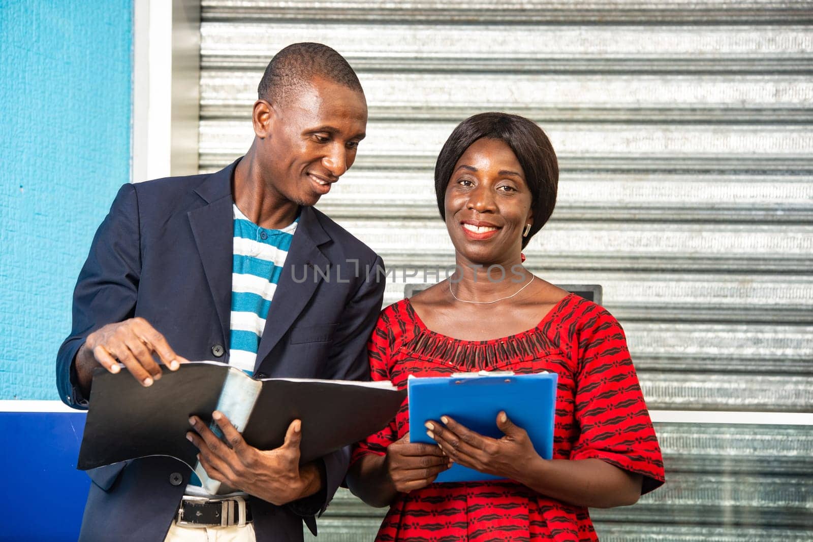 handsome african businessman looking at document file on hand of african businesswoman outdoors