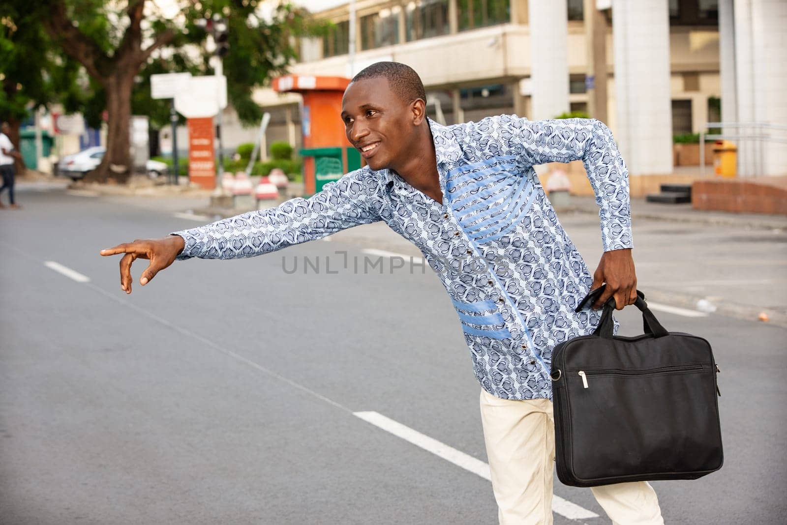 young businessman standing by the roadside beckoning to a car smiling