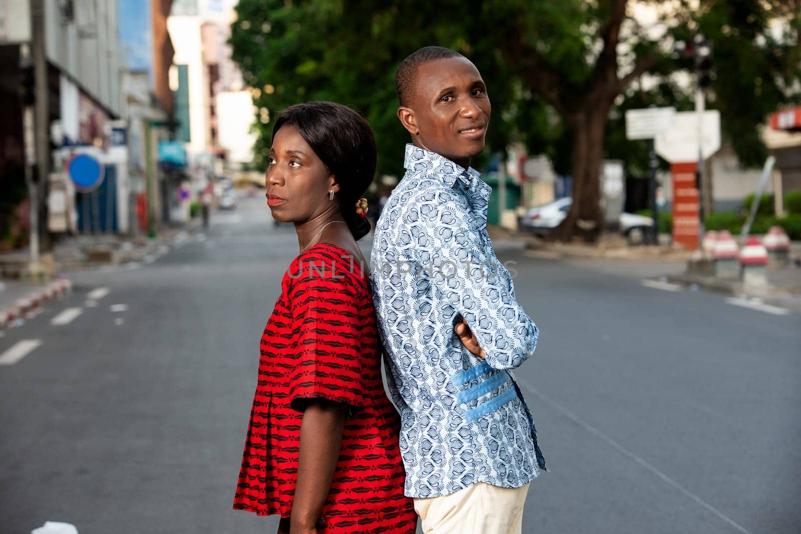 Businessman and african businessman standing back to back in the street outdoors while smiling