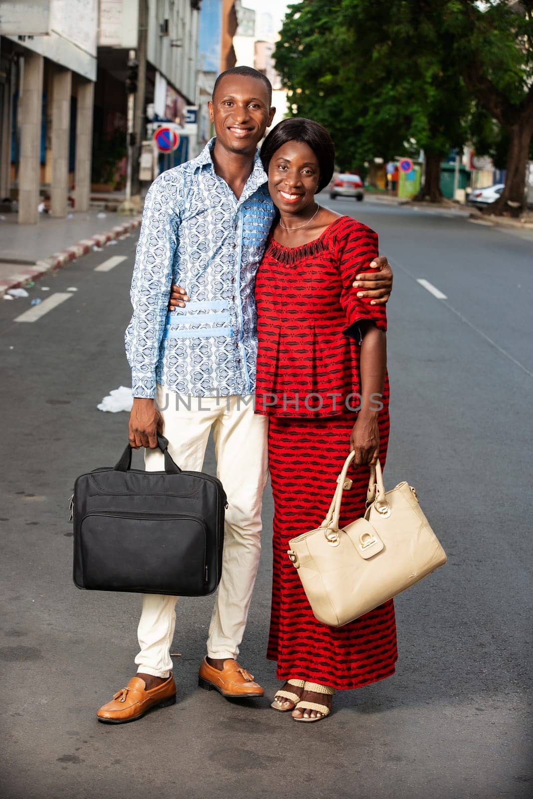 beautiful adult businesswoman dressed in red loincloth walking with her partner wearing a shirt jeans holding hands together on the street being happy