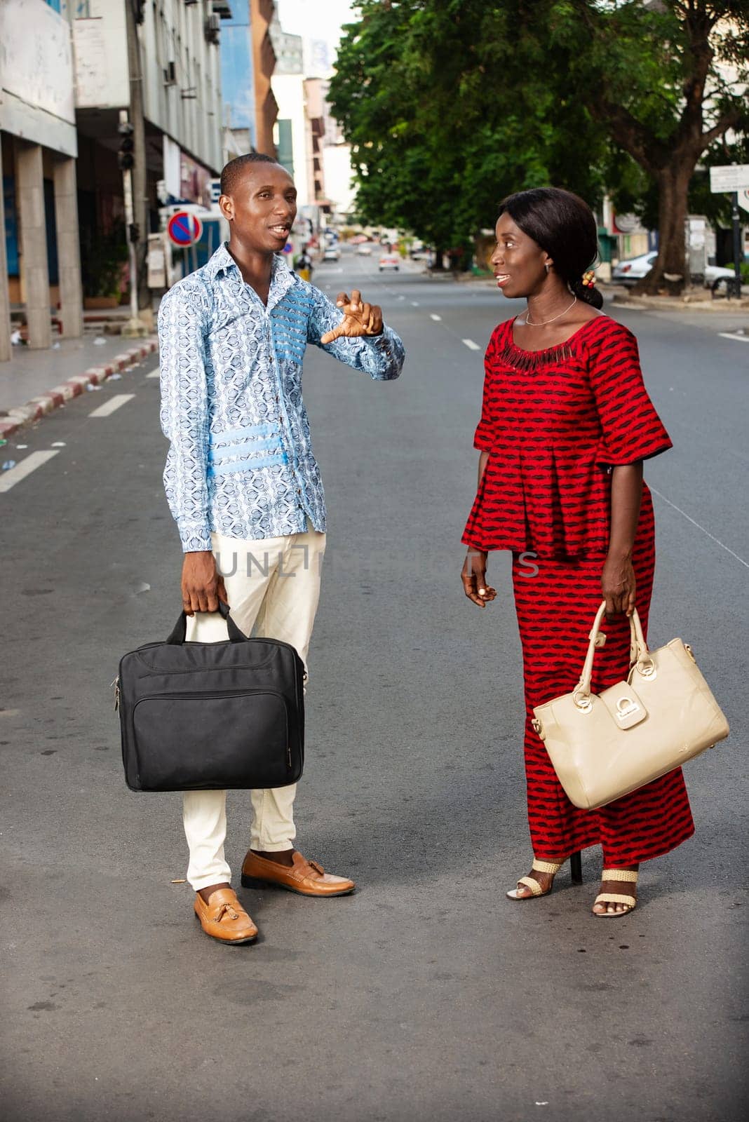 beautiful adult businesswoman dressed in red loincloth walking together with her partner wearing a shirt and jeans on the street being happy