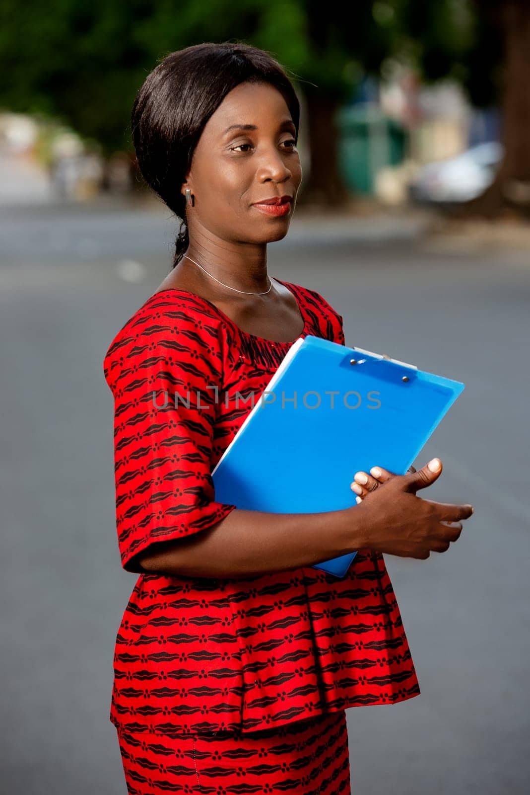 beautiful businesswoman dressed in loincloth holding in hand a blue document smiling in the street