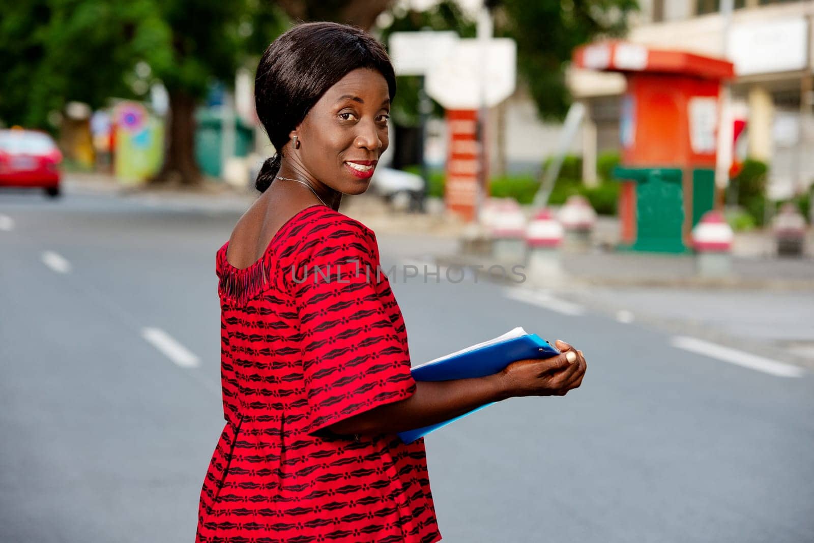 beautiful businesswoman dressed in loincloth holding in hand a blue document smiling in the street