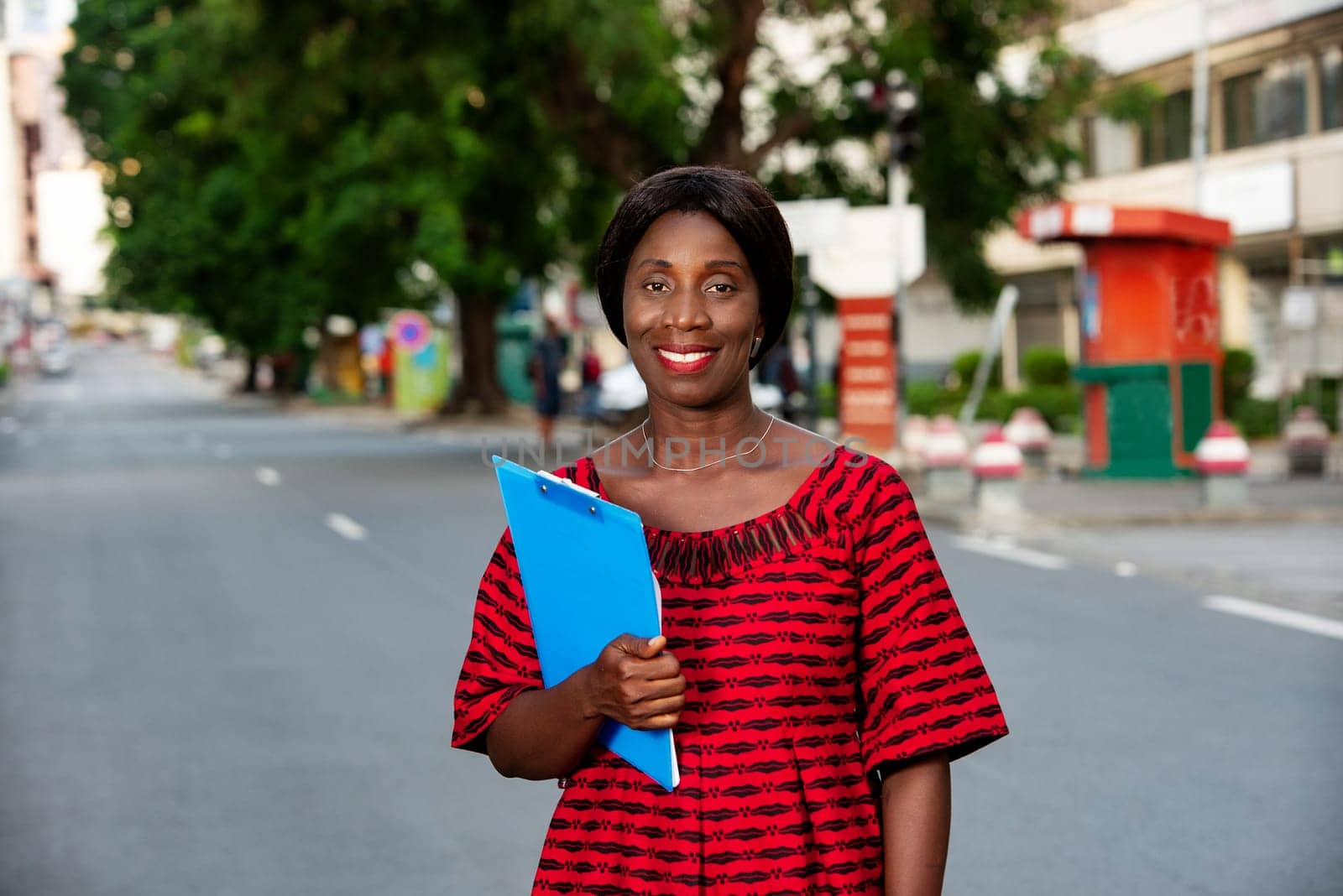 beautiful businesswoman dressed in loincloth holding in hand a blue document smiling in the street